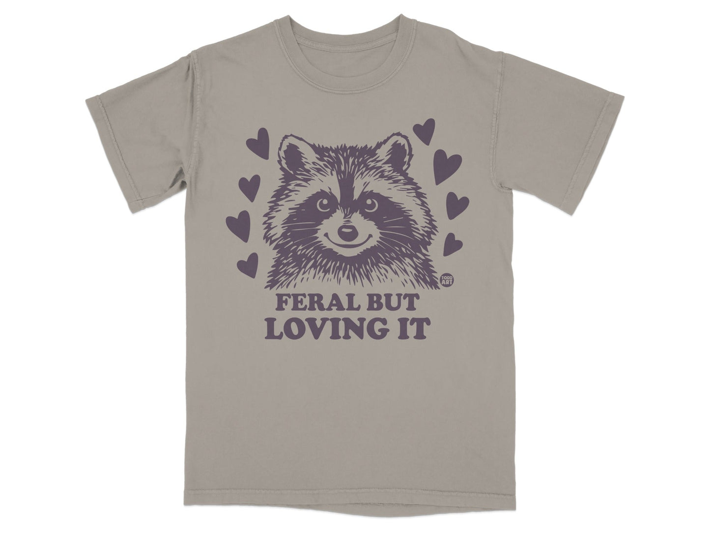 T-shirt with a raccoon graphic and text "FERAL BUT LOVING IT" surrounded by hearts.