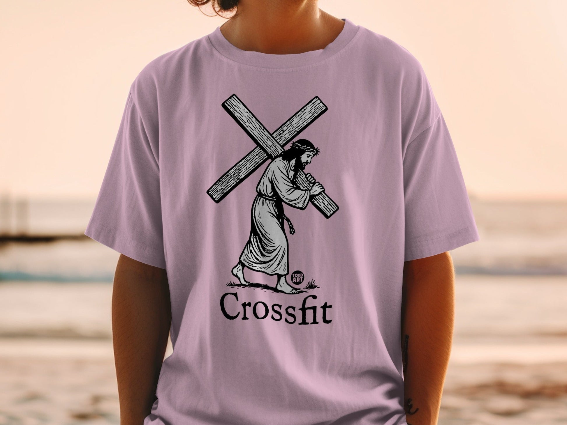 Jesus carrying the cross on a lilac t-shirt with "Crossfit" text.