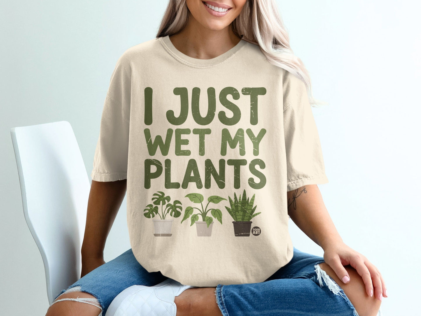 Cream t-shirt with green text "I JUST WET MY PLANTS" and three potted plants.