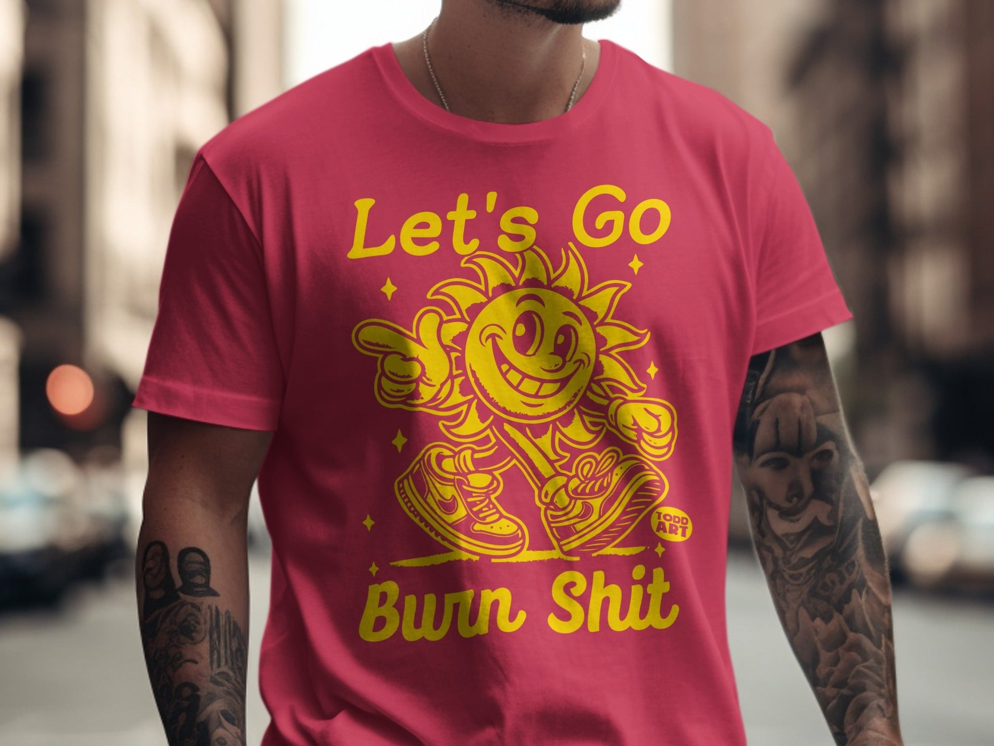Pink t-shirt with cartoon sun graphic and text "Let's Go Burn Shit".