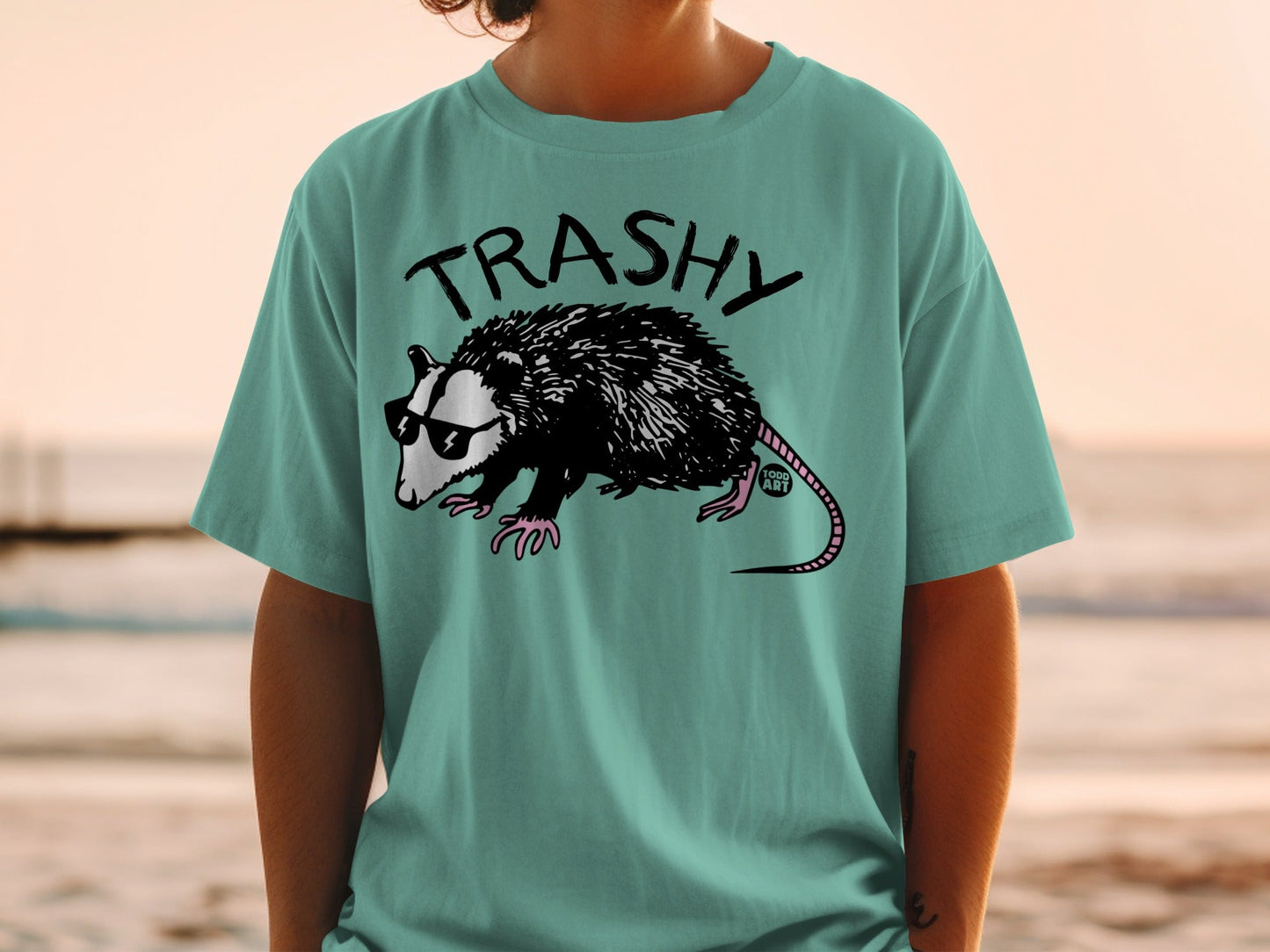 Opossum in sunglasses wearing a t-shirt with the word "TRASHY".