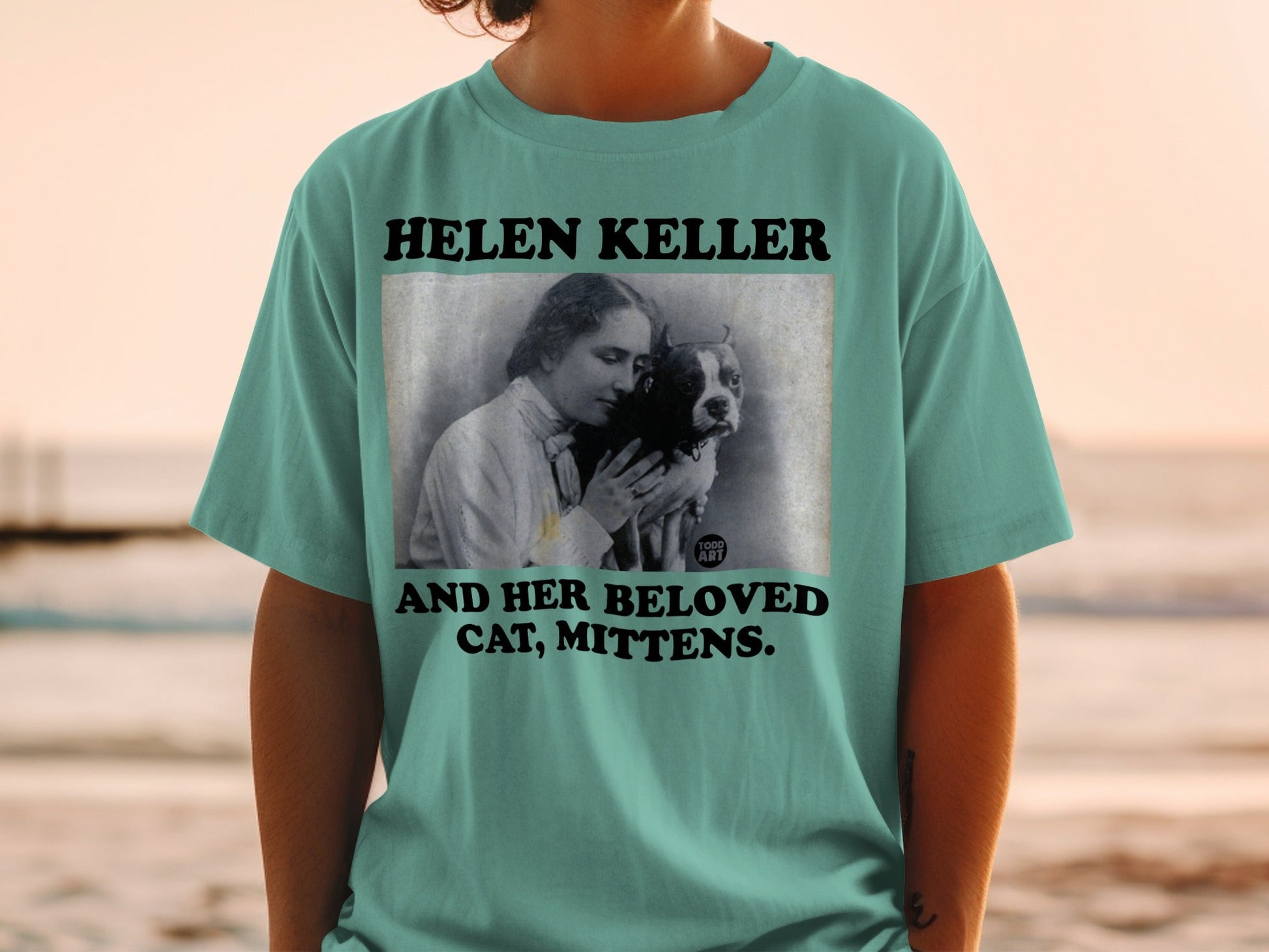 Helen Keller and cat graphic on teal t-shirt.