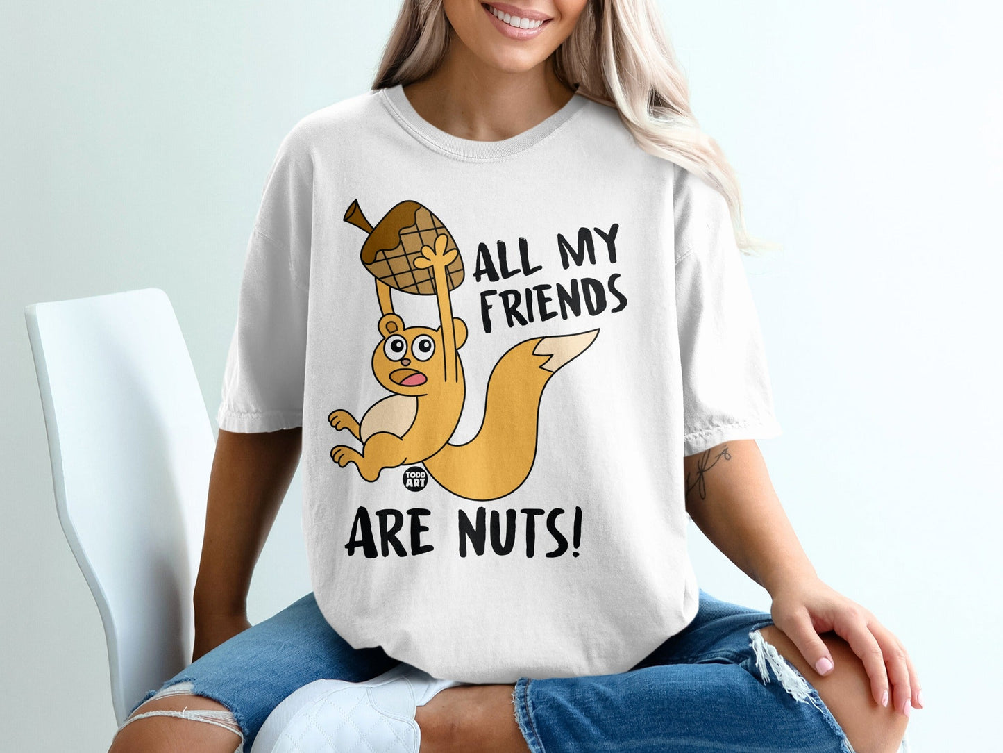 White t-shirt with cartoon squirrel holding acorn, text "ALL MY FRIENDS ARE NUTS!".