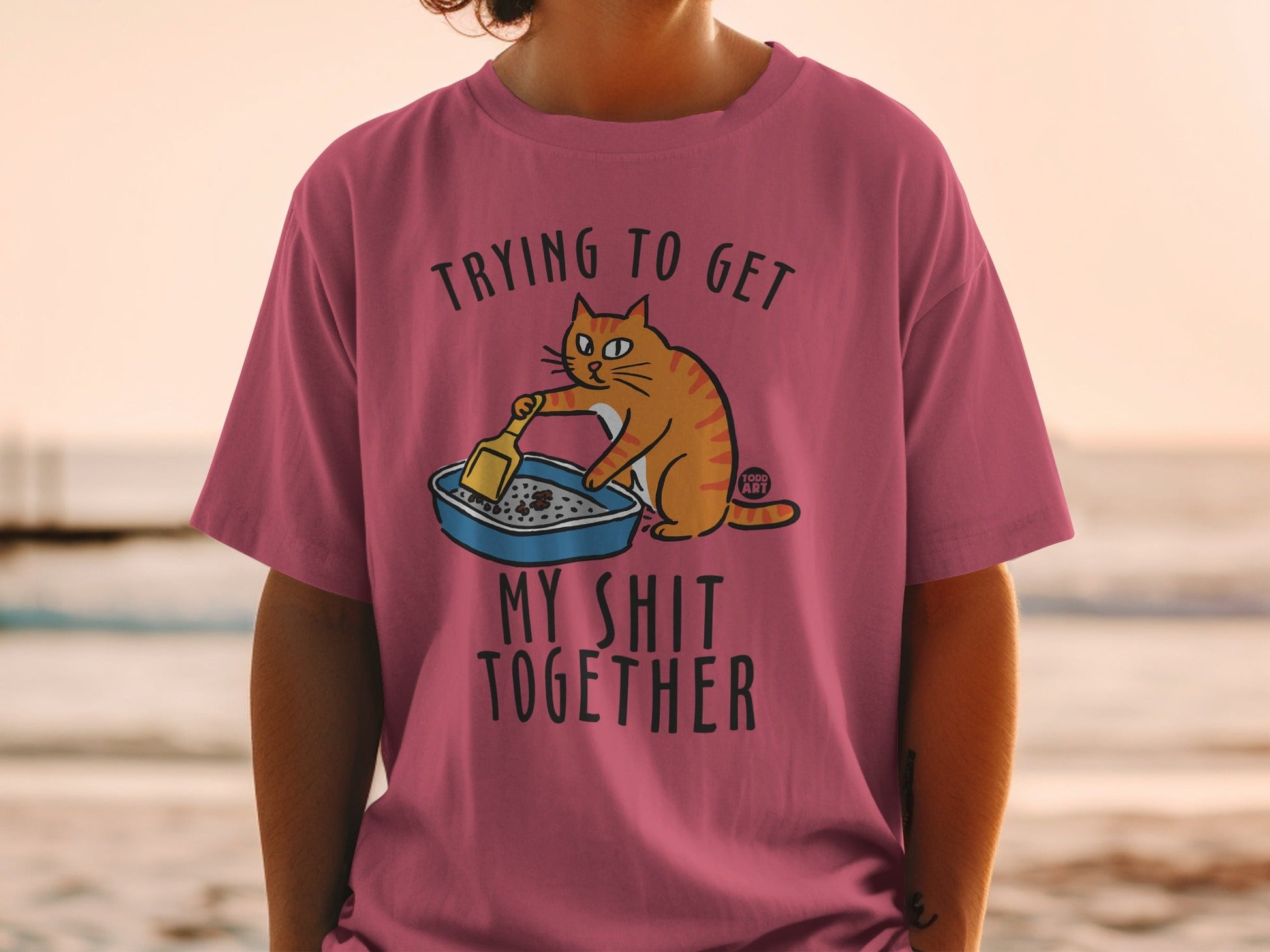 T-shirt with text "Trying to get my shit together" and cartoon cat cleaning litter box.