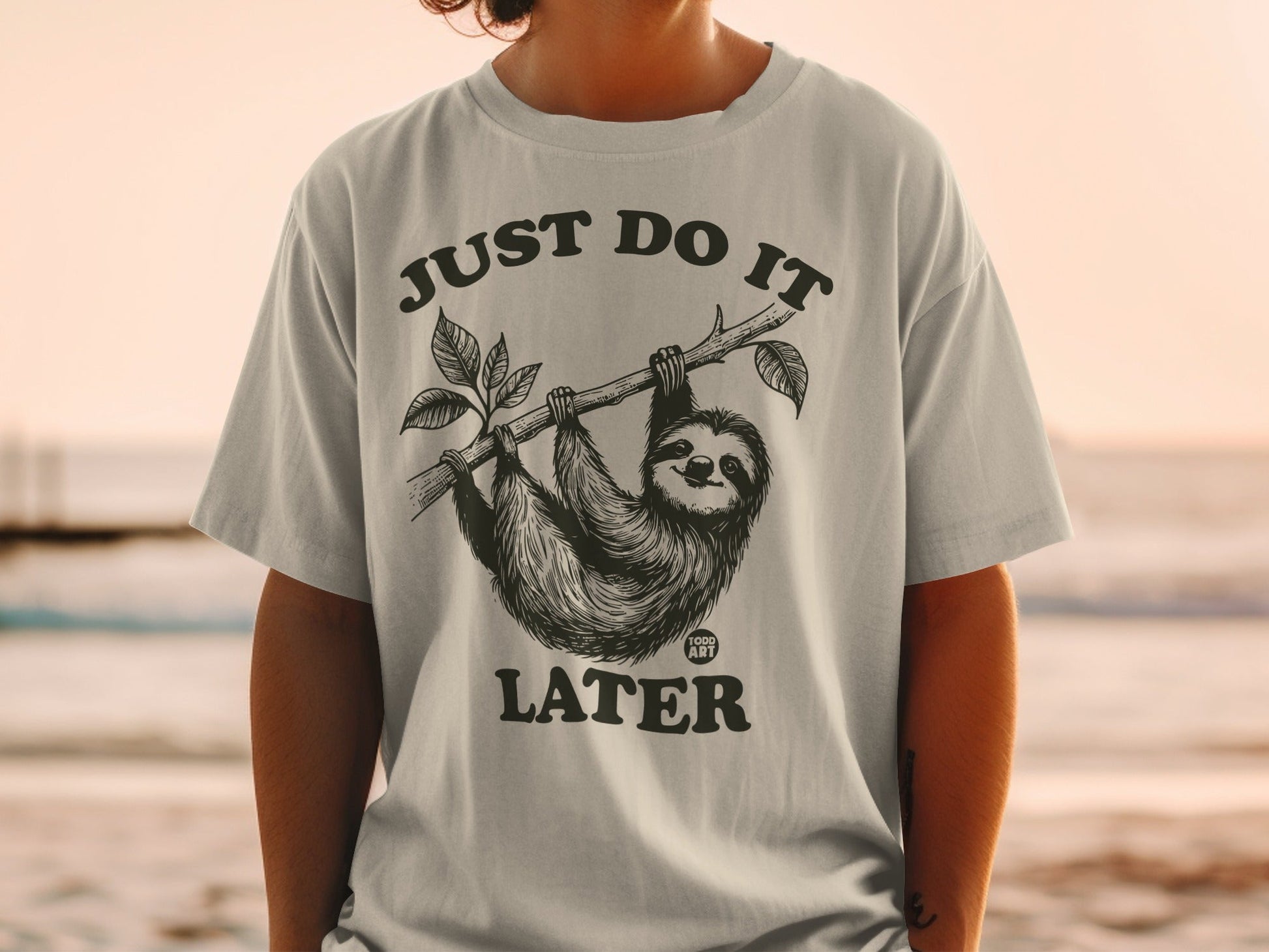 T-shirt with a sloth hanging from a branch, text "JUST DO IT LATER".