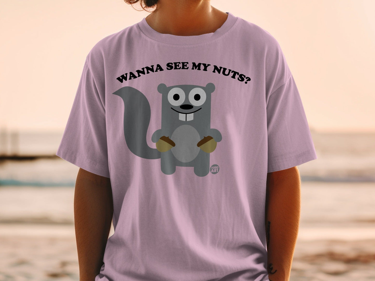 Pink t-shirt with a cartoon squirrel holding acorns and text "WANNA SEE MY NUTS?".
