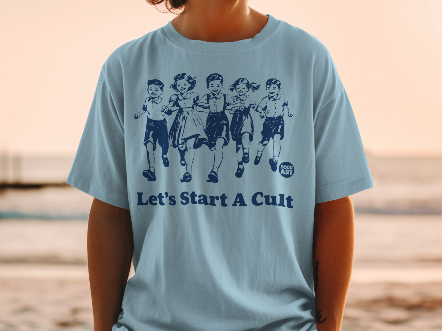 Light blue t-shirt with cartoon children running and text "Let's Start A Cult".