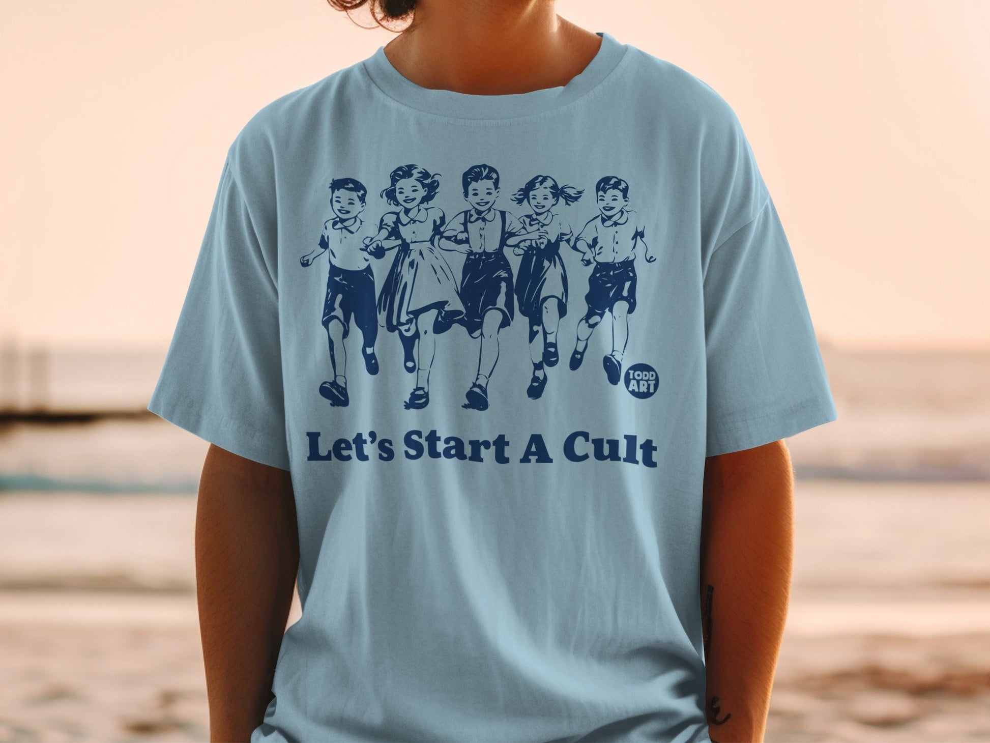 Light blue t-shirt with cartoon children running and text "Let's Start A Cult".