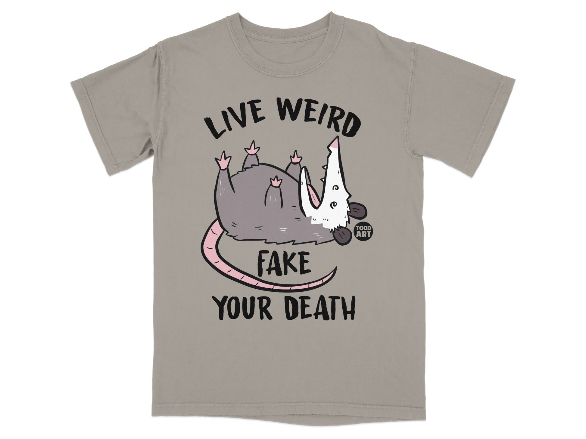 Gray opossum with text "LIVE WEIRD FAKE YOUR DEATH" on a taupe t-shirt.
