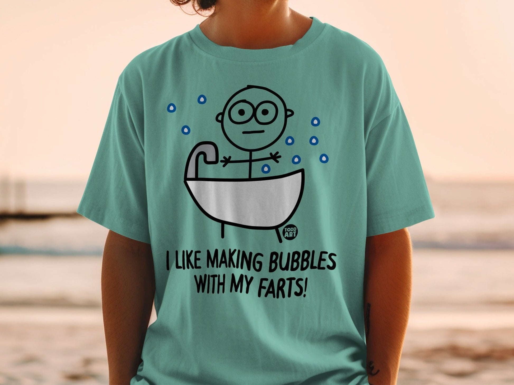 Teal t-shirt with cartoon figure in bathtub, "I LIKE MAKING BUBBLES WITH MY FARTS!"