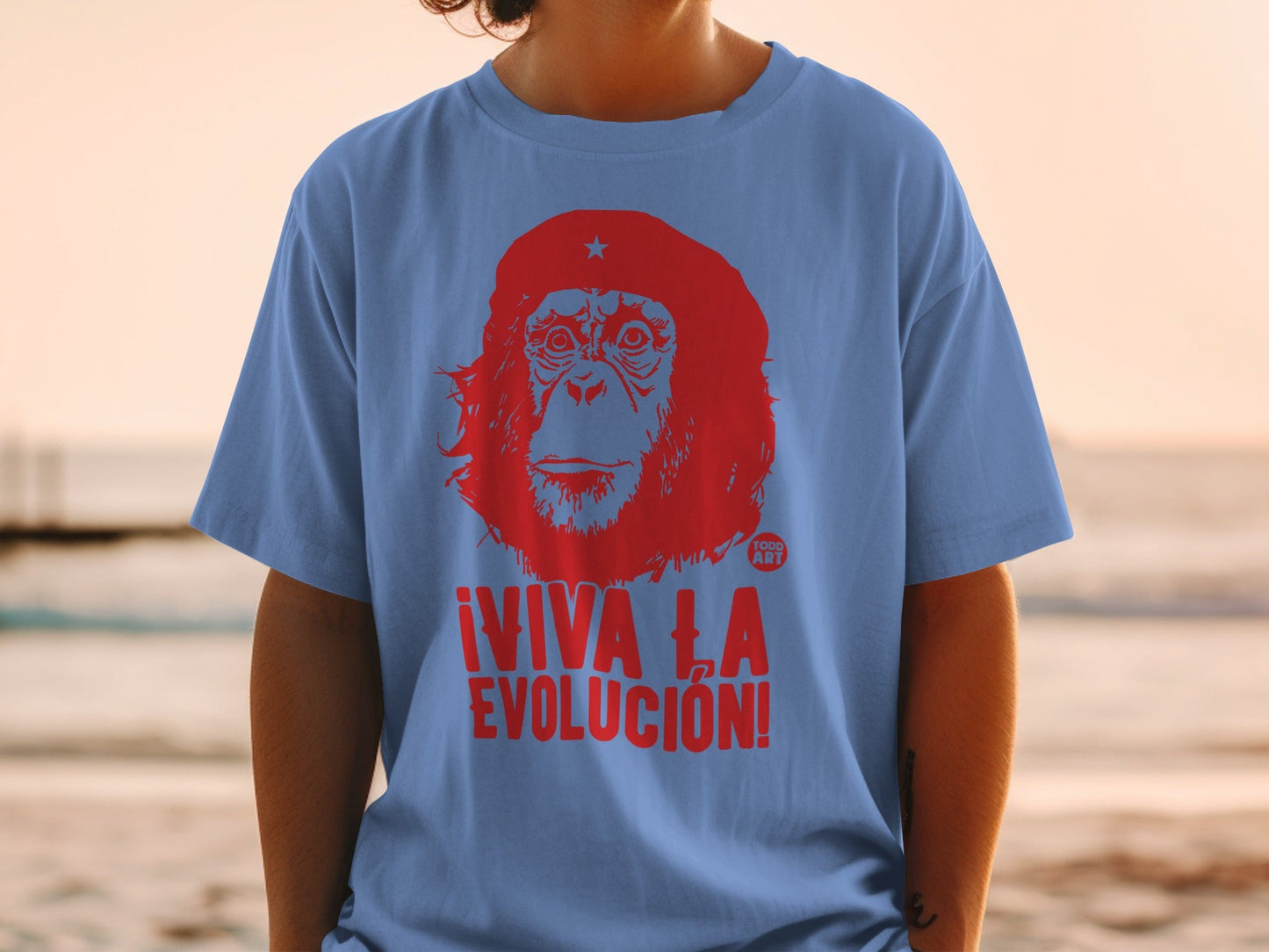 Blue t-shirt with red graphic of a chimpanzee face and "¬°VIVA LA EVOLUCI√ìN!" text.
