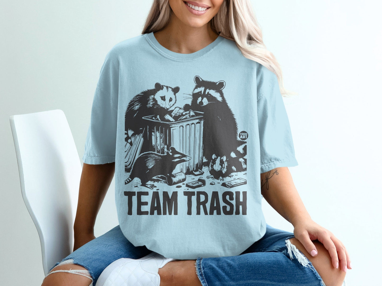 Light blue t-shirt with "TEAM TRASH" slogan and raccoon and possum graphic.