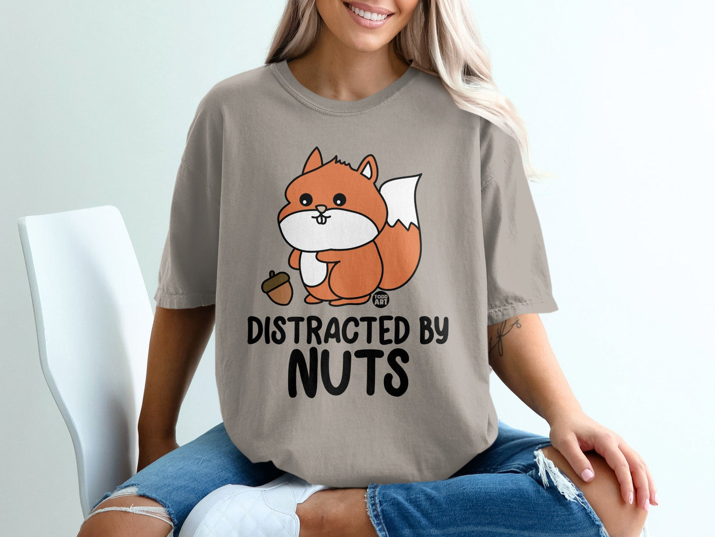 T-shirt with cartoon squirrel holding acorn and "Distracted by Nuts" text.