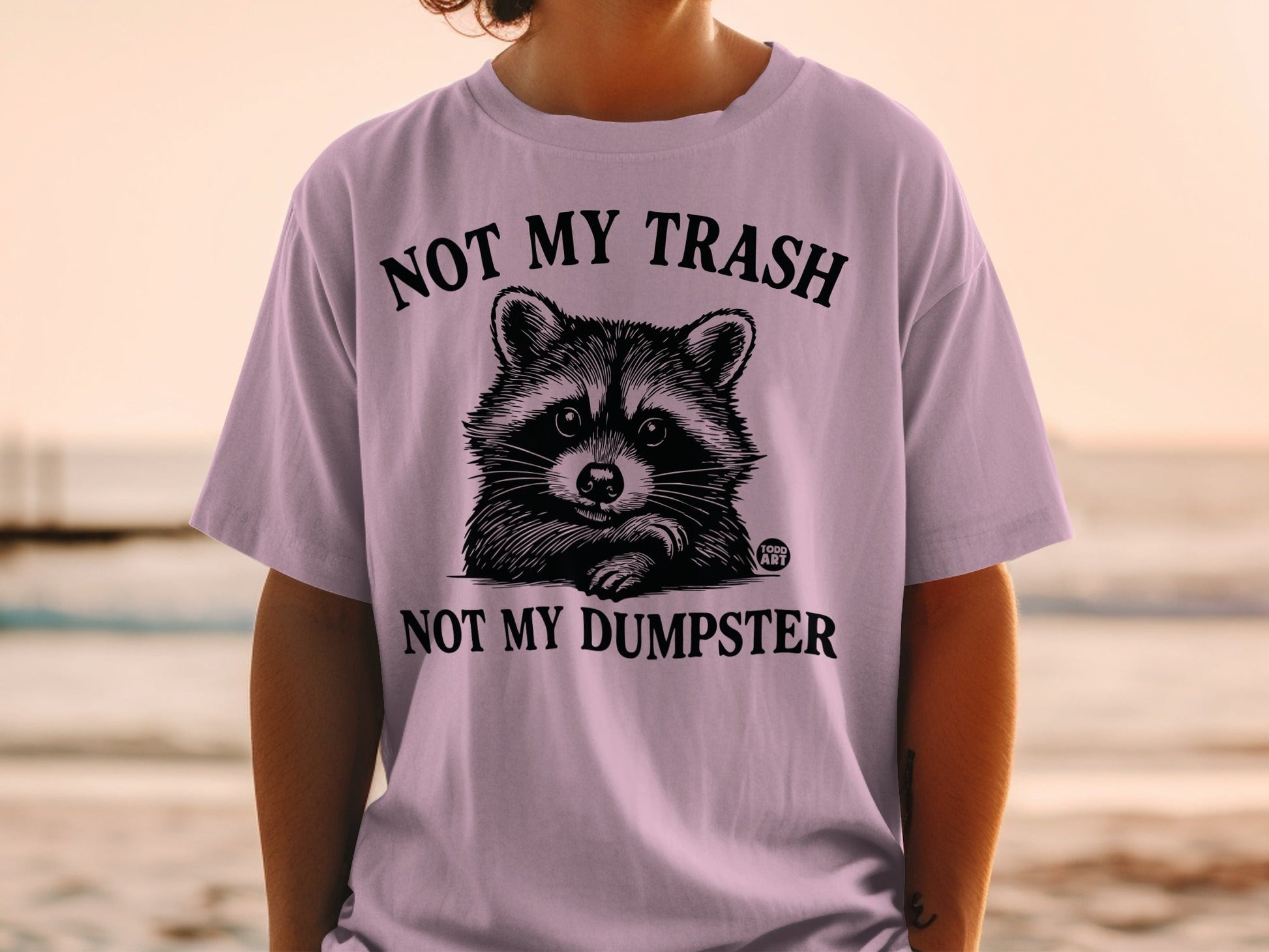 T-shirt with raccoon illustration and text "NOT MY TRASH NOT MY DUMPSTER".