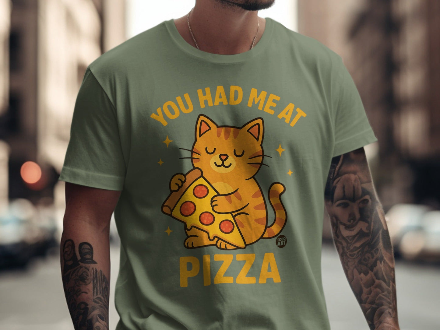 Green t-shirt with cartoon cat holding pizza and text "YOU HAD ME AT PIZZA".