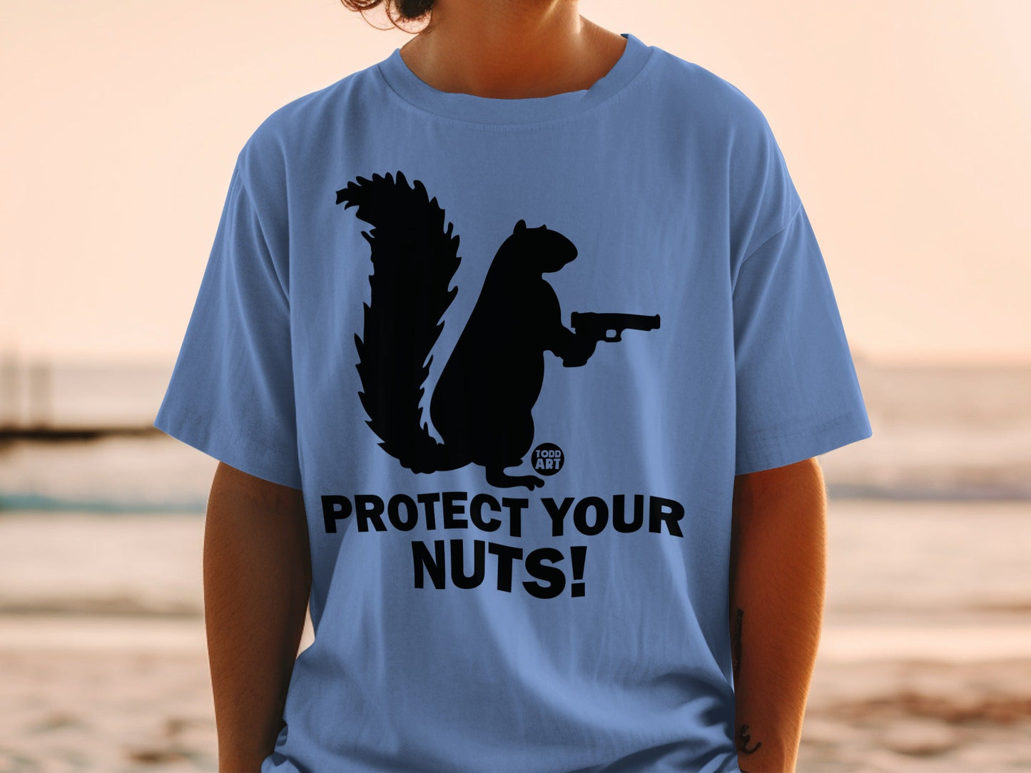 Blue t-shirt with black squirrel silhouette holding a gun, "Protect Your Nuts!" text.
