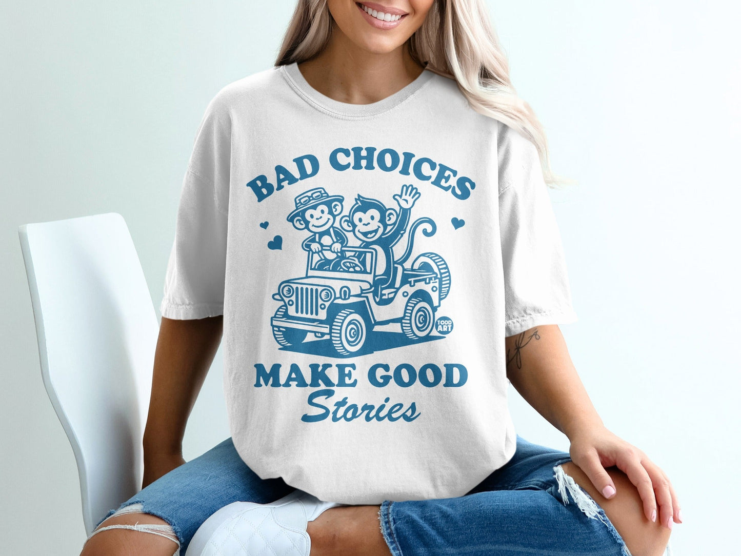 White t-shirt with "Bad Choices Make Good Stories" and cartoon monkeys in a jeep.
