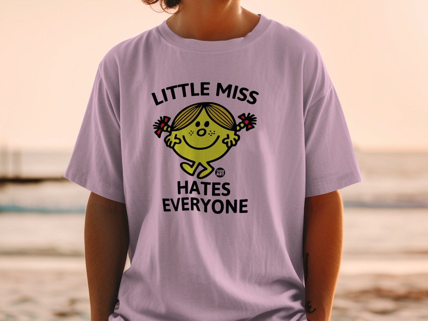 Lilac t-shirt with "Little Miss Hates Everyone" graphic and cartoon character.