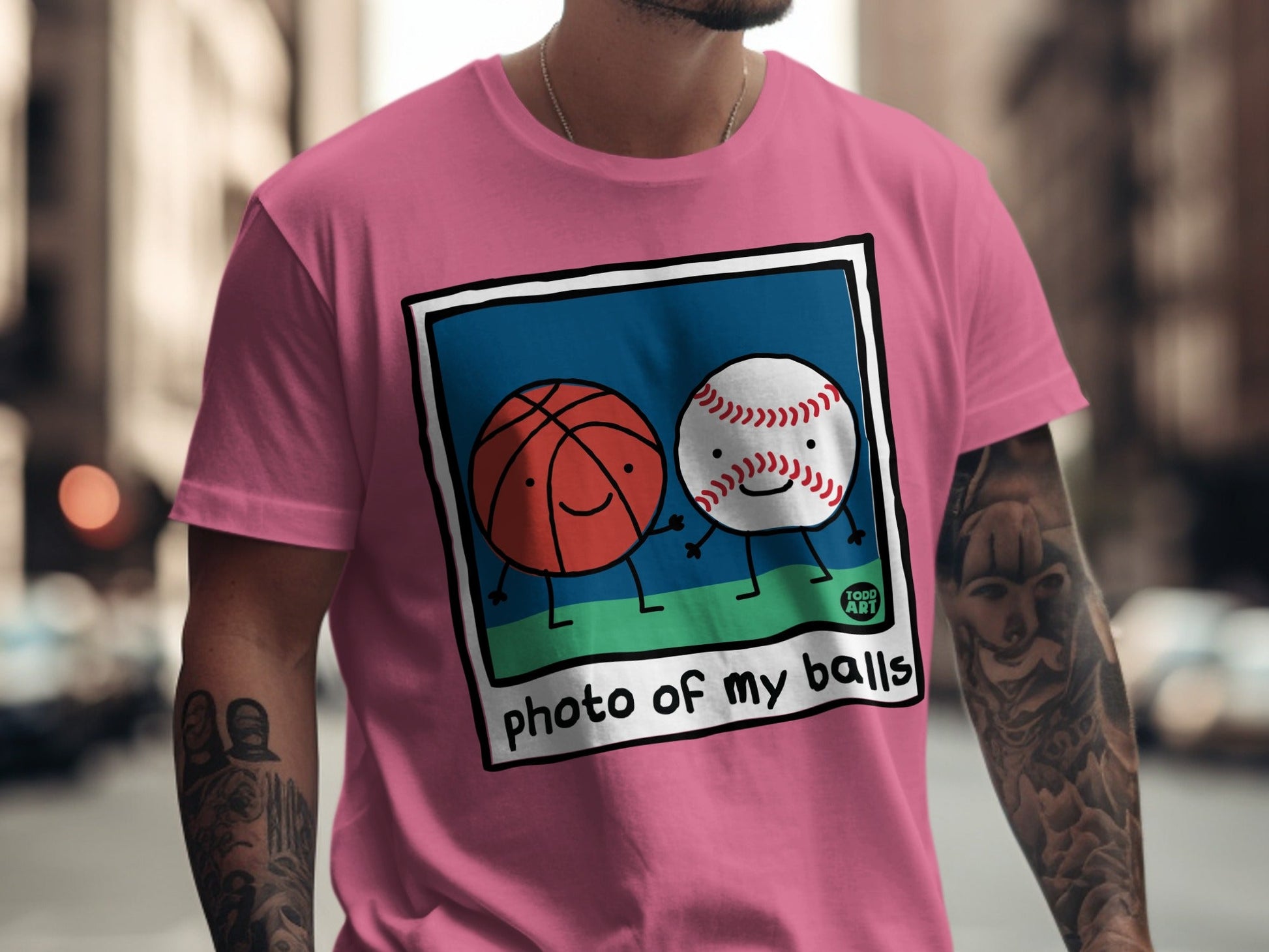 Pink t-shirt with cartoon basketball and baseball holding hands.