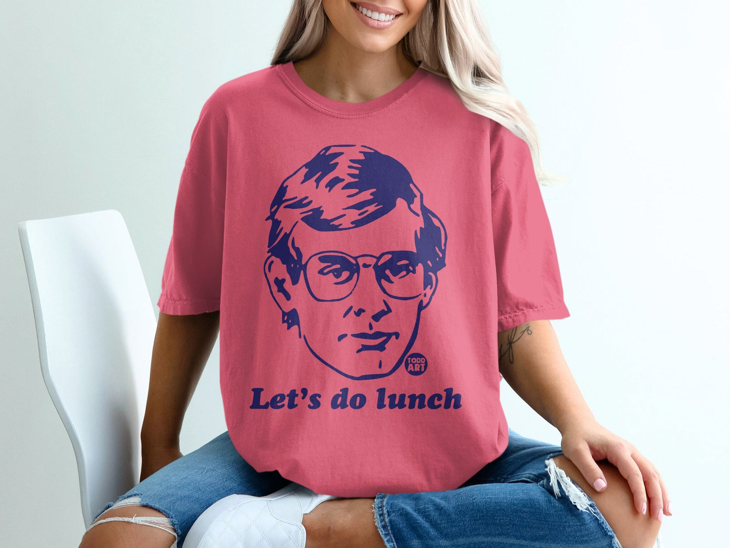 Woman wearing pink t-shirt with graphic of man's face and text "Let's do lunch."