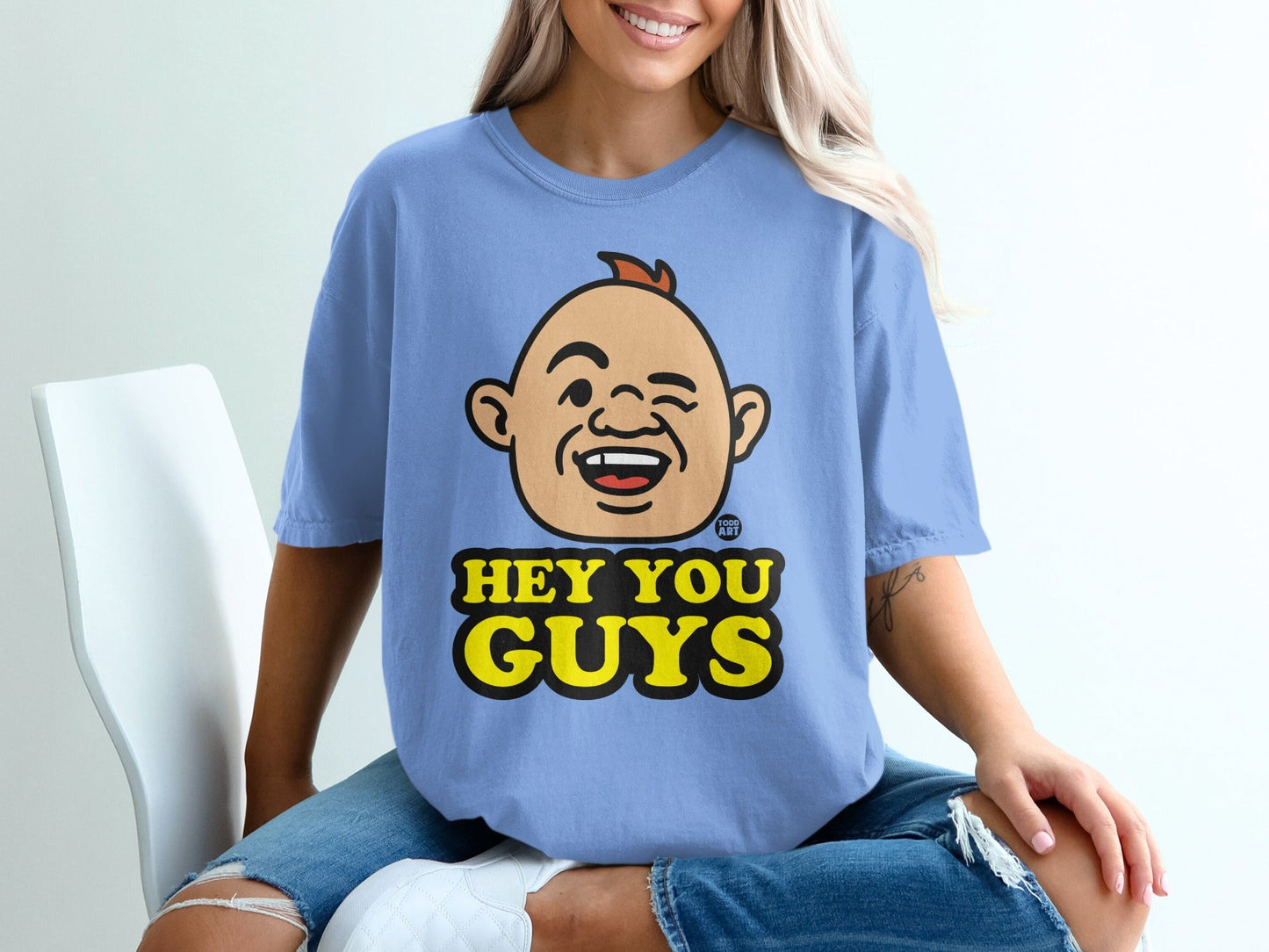 Blue t-shirt with a cartoon face winking and the text "HEY YOU GUYS".
