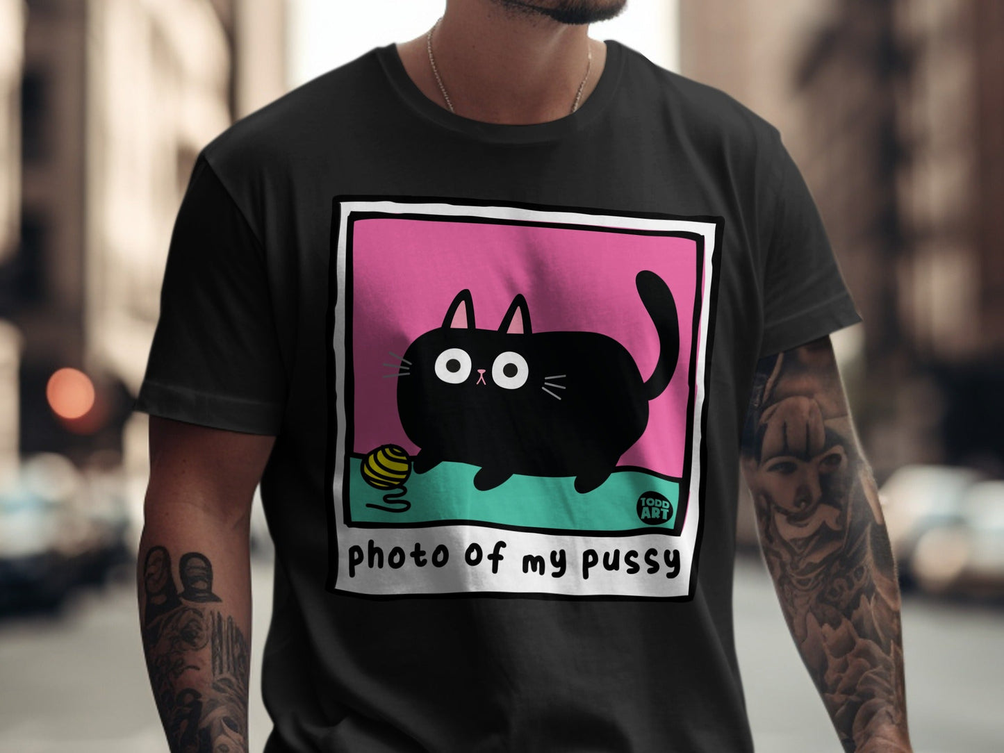 Black cartoon cat with yarn ball on pink and green background, "photo of my pussy" text.