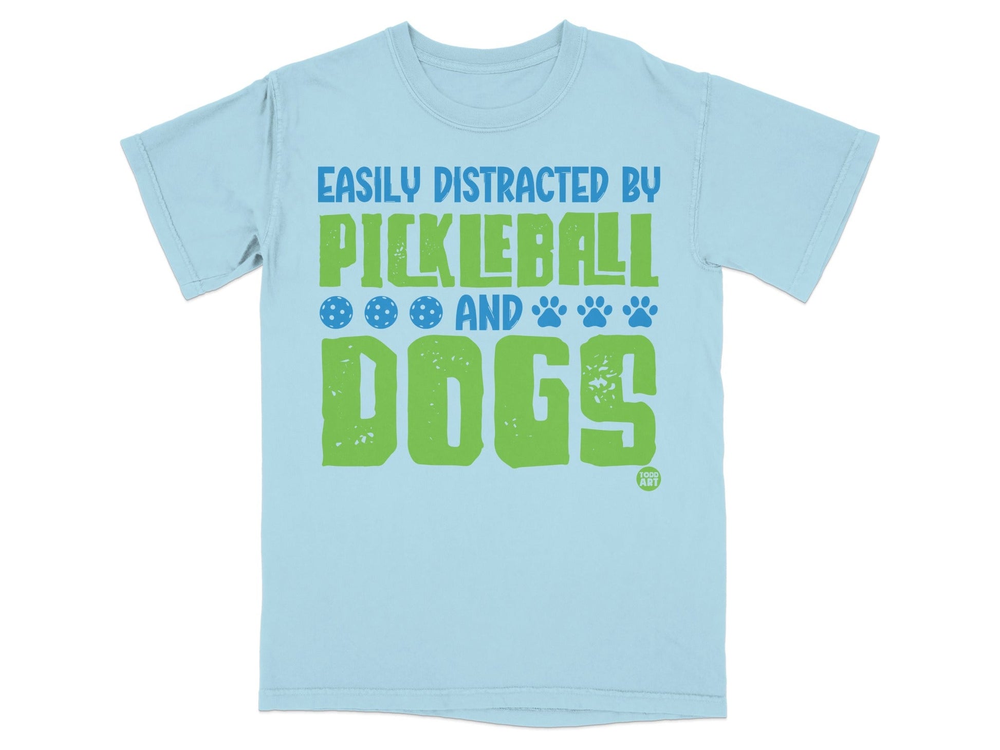 Light blue t-shirt with green text "Easily Distracted By Pickleball And Dogs" and paw prints.
