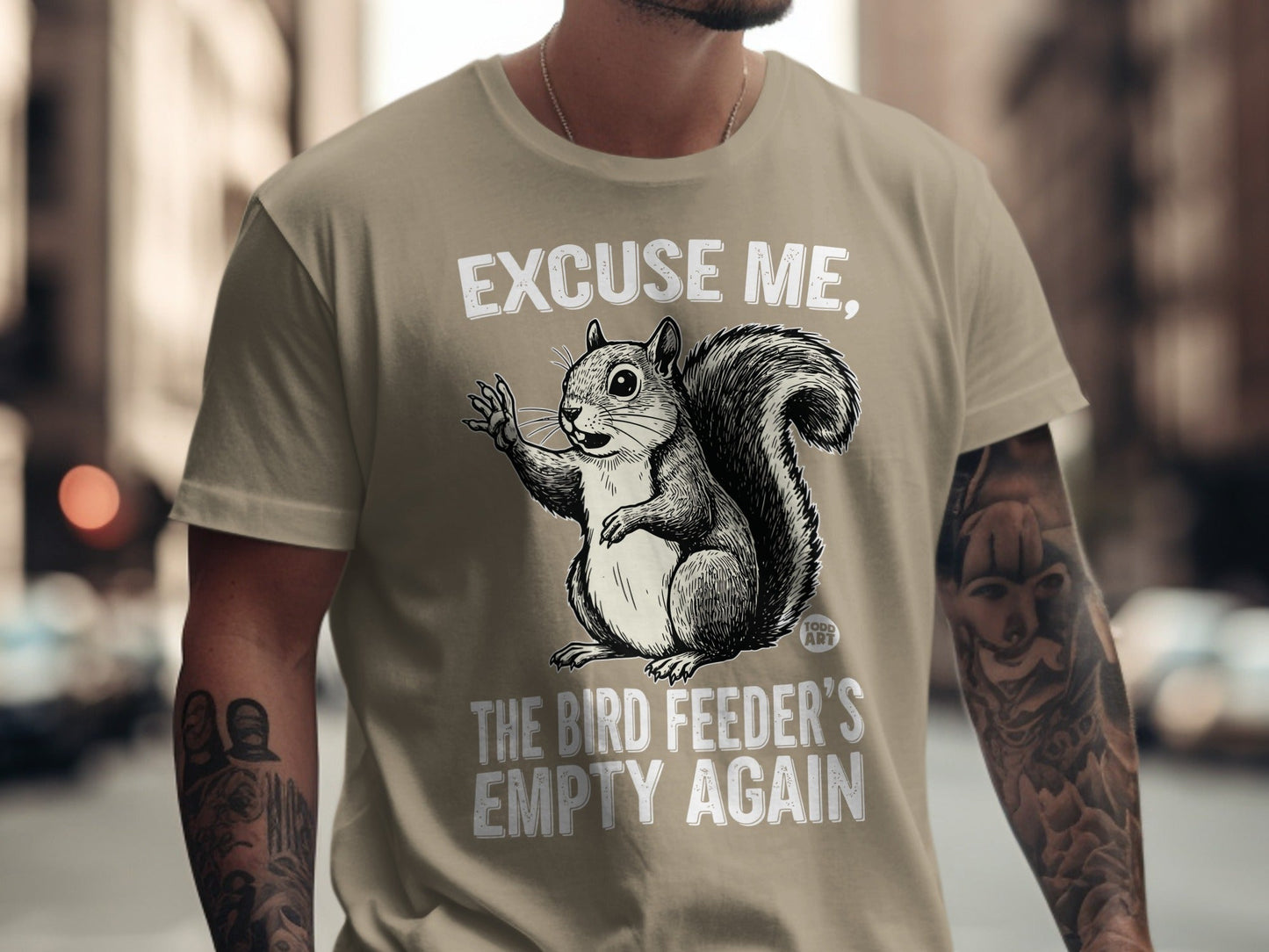 T-shirt with a squirrel illustration and text "EXCUSE ME, THE BIRD FEEDER'S EMPTY AGAIN".
