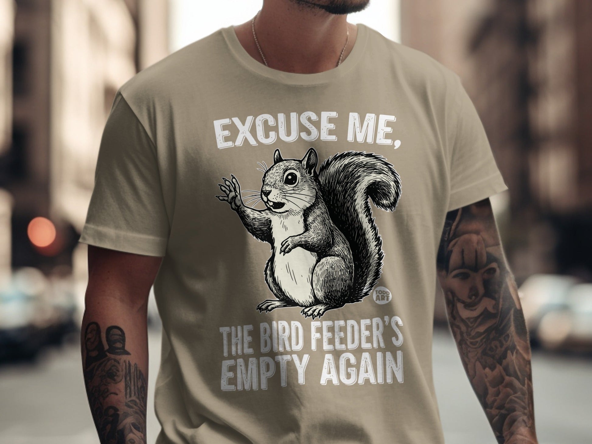 T-shirt with a squirrel illustration and text "EXCUSE ME, THE BIRD FEEDER'S EMPTY AGAIN".