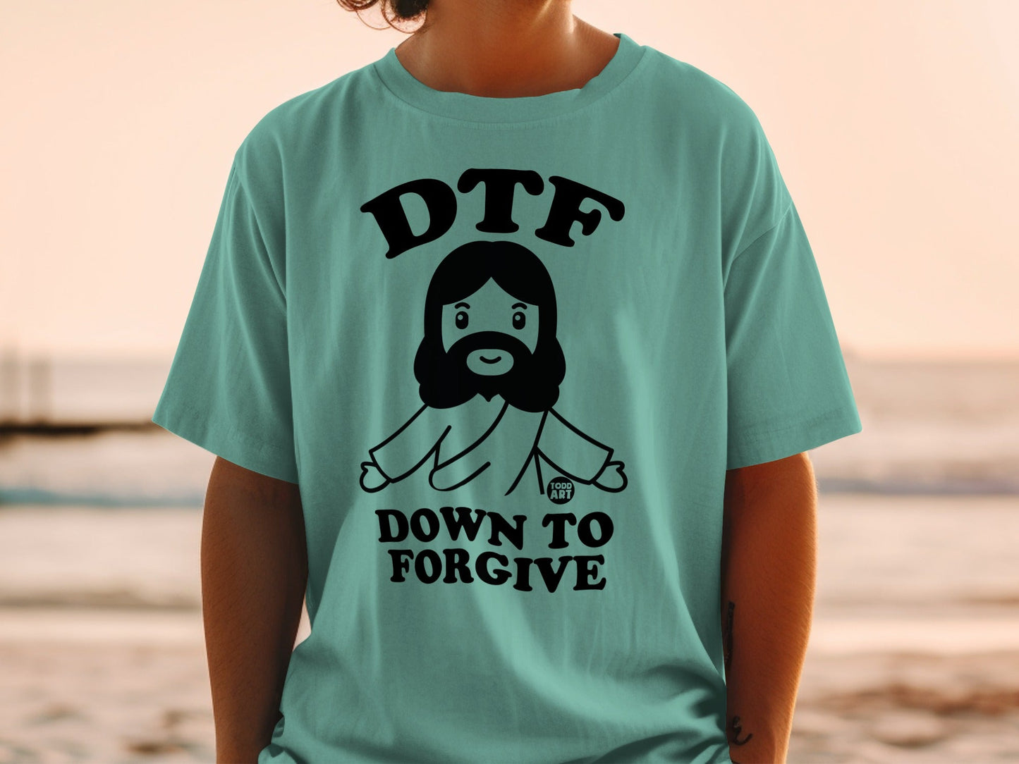 Teal t-shirt with "DTF DOWN TO FORGIVE" and cartoon Jesus graphic.