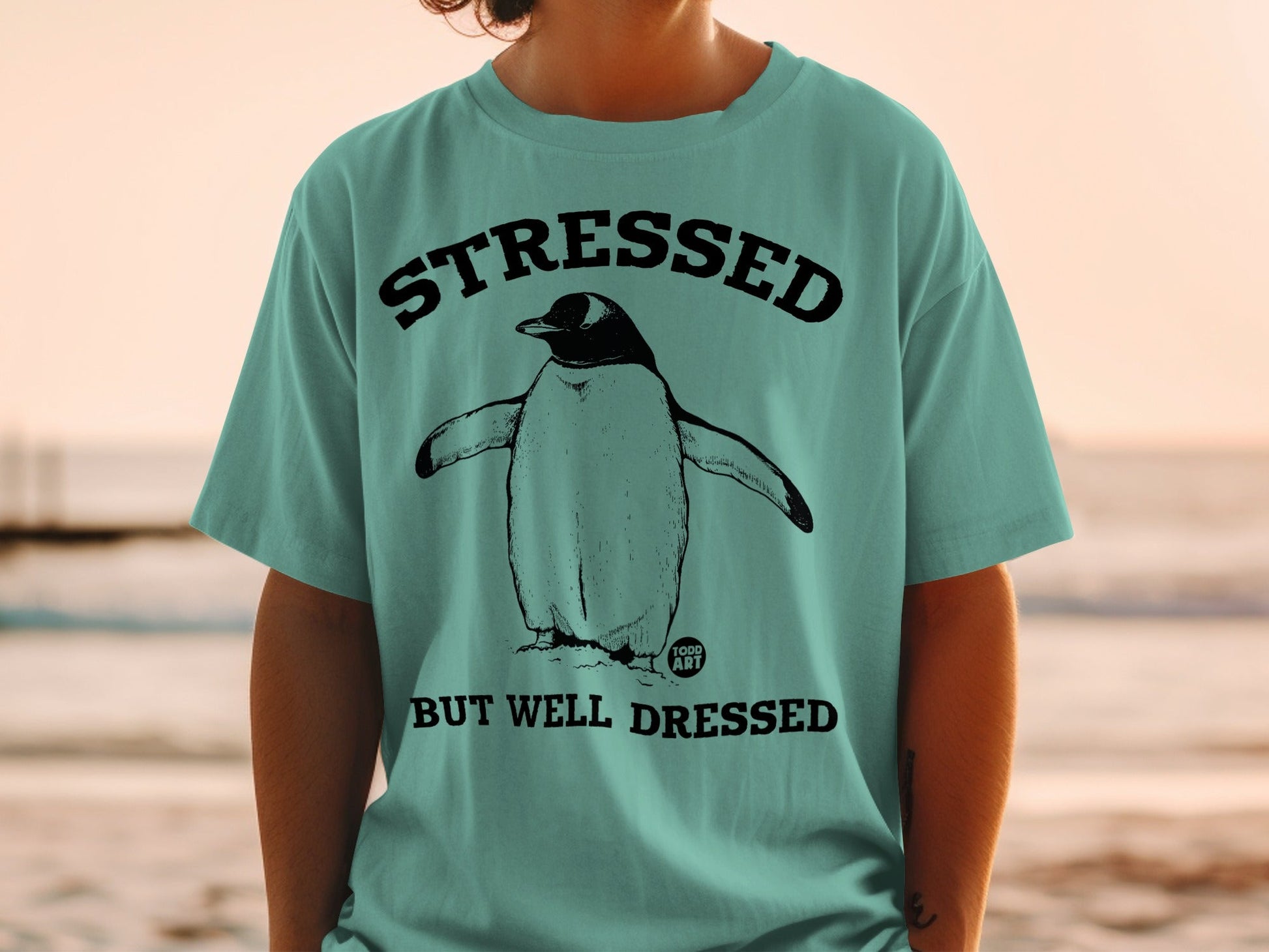 T-shirt with penguin graphic and text "STRESSED BUT WELL DRESSED".