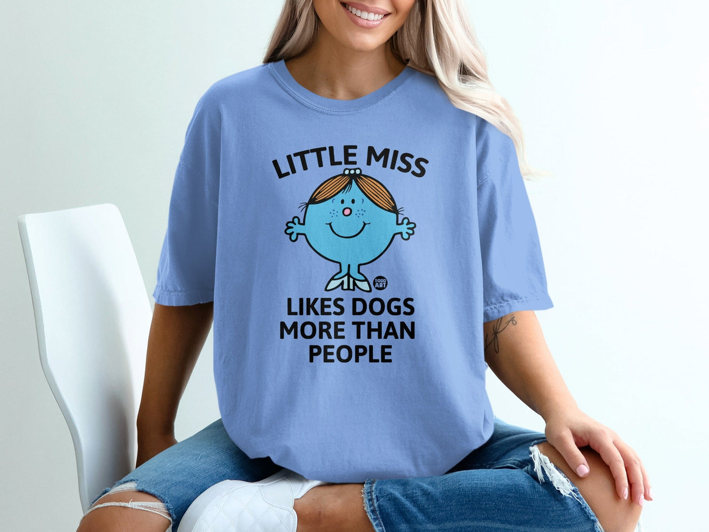 Light blue t-shirt with "Little Miss Likes Dogs More Than People" text and character.