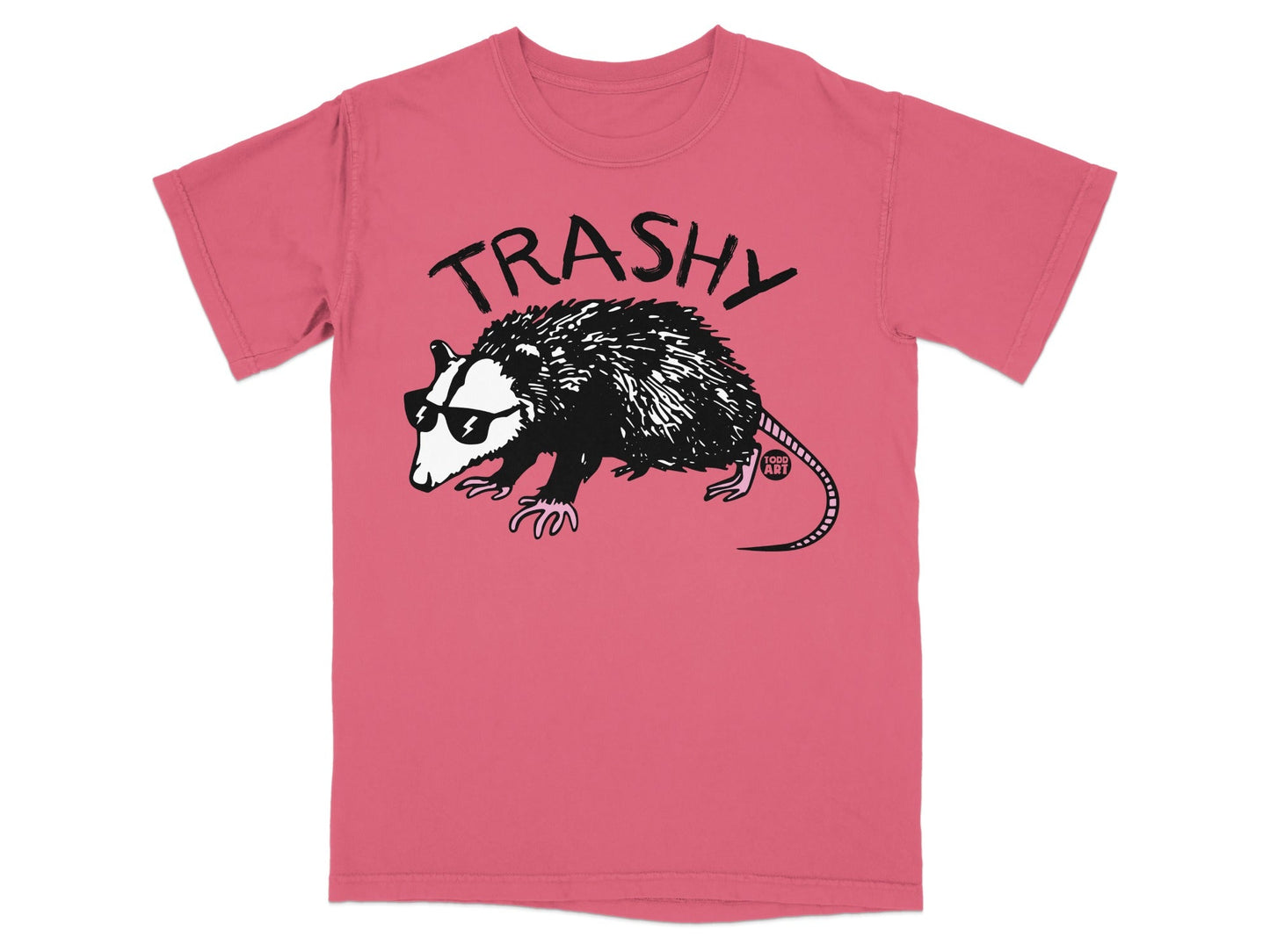 Pink t-shirt with a black line drawing of a raccoon wearing sunglasses and the word "TRASHY" above it.