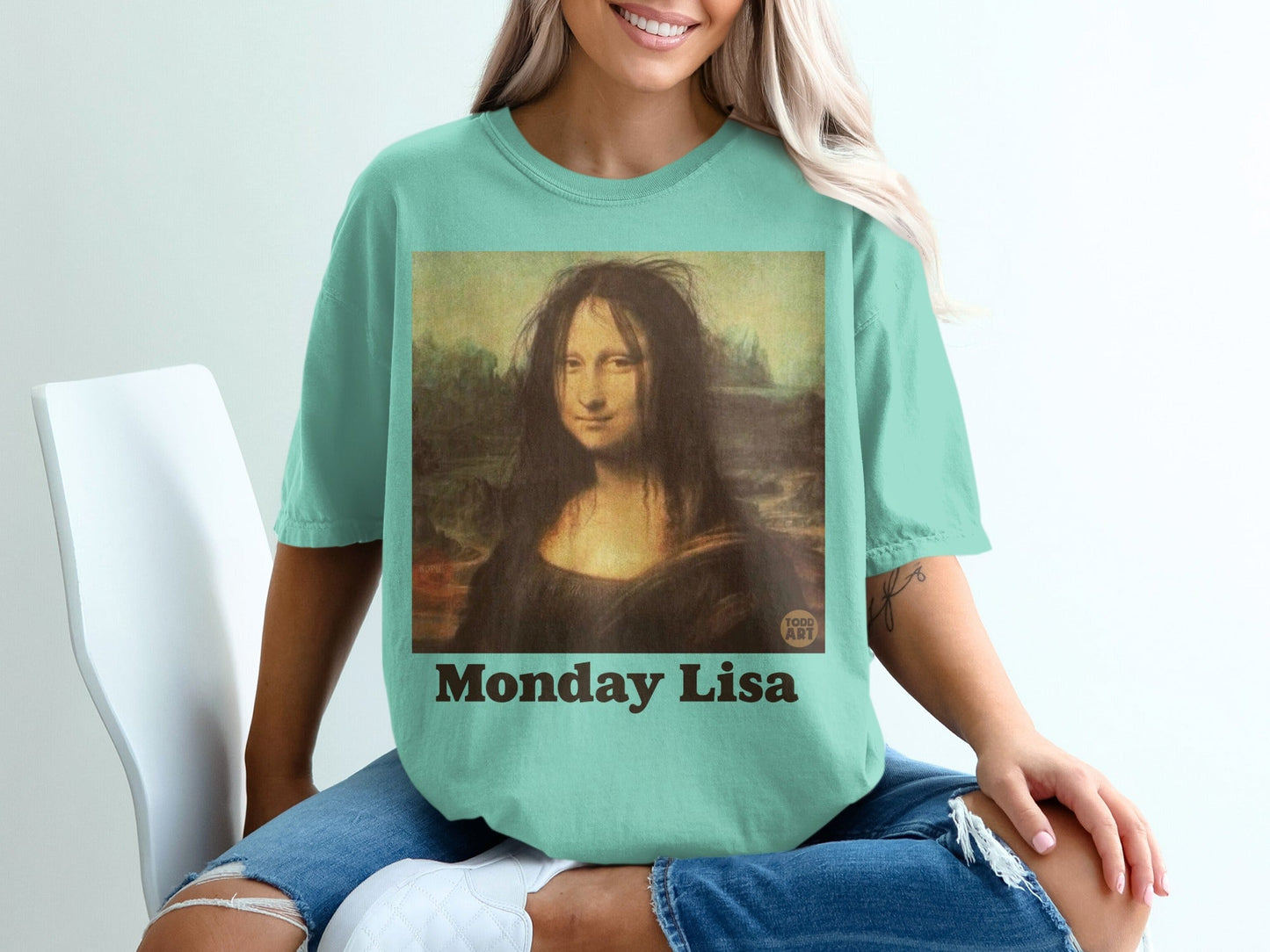 Mona Lisa with messy hair, wearing a teal t-shirt that says "Monday Lisa."