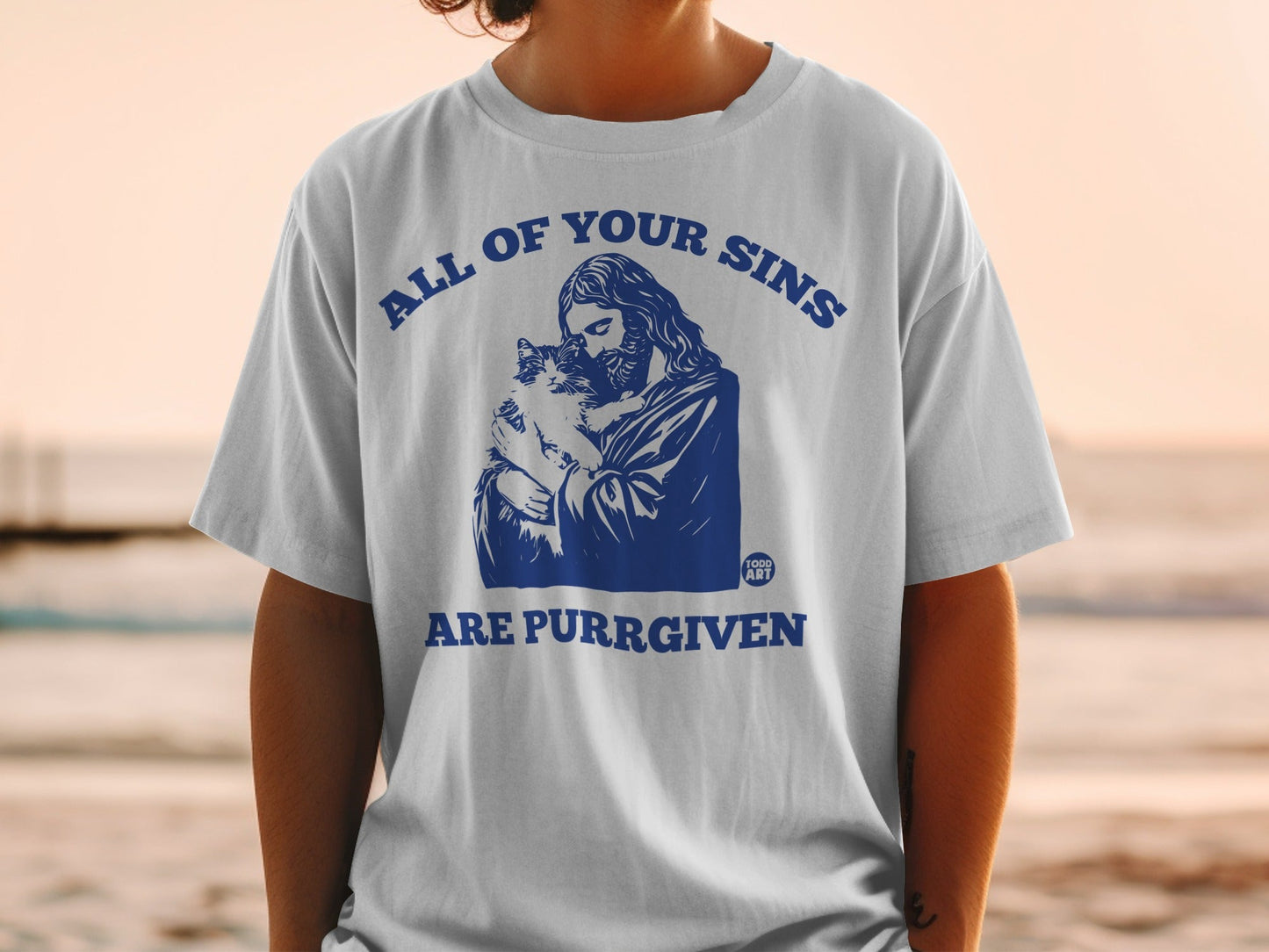 White t-shirt with Jesus holding a cat, text reads "All of your sins are purrgiven".