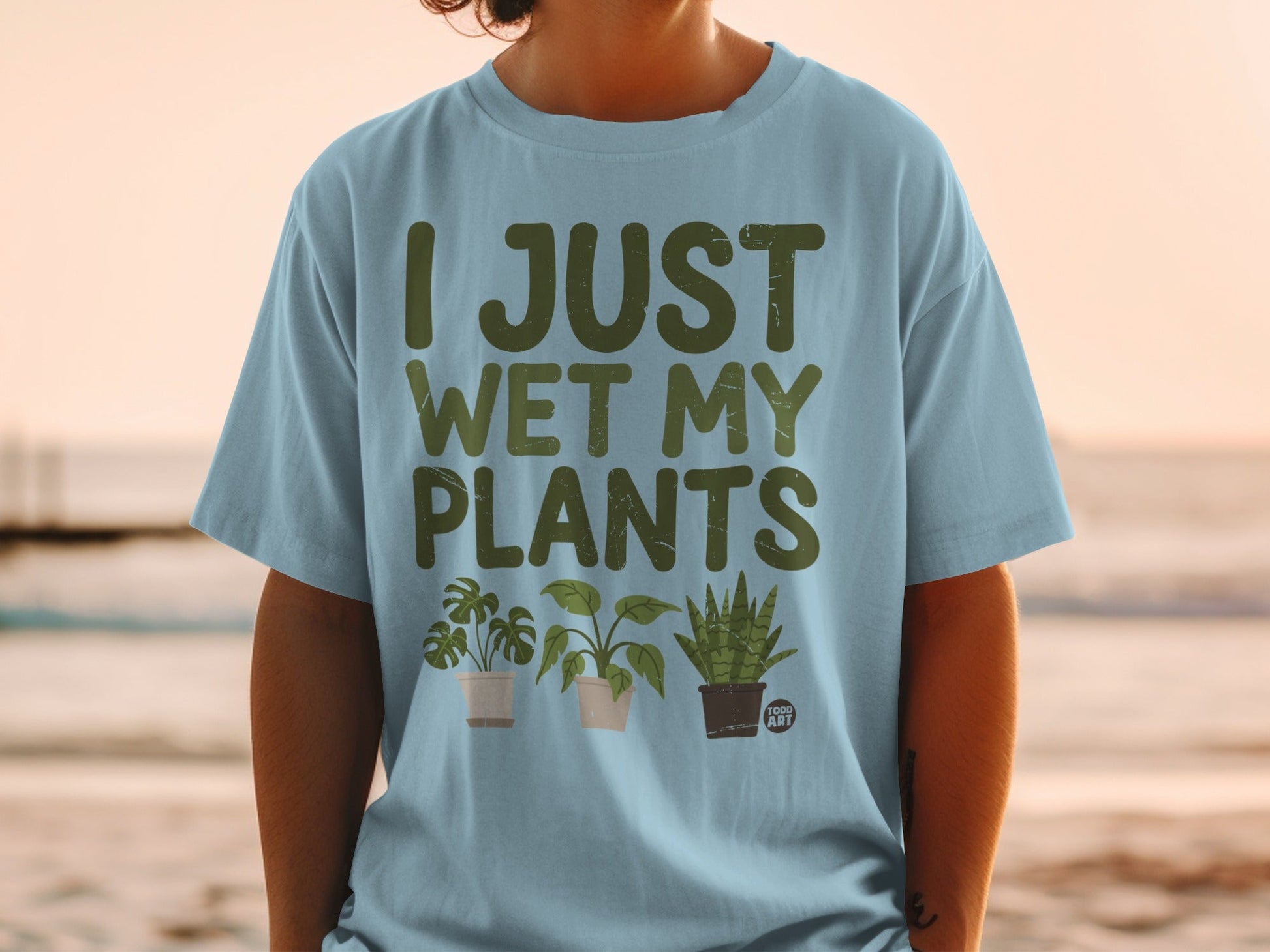 Light blue t-shirt with "I JUST WET MY PLANTS" and cartoon potted plants.