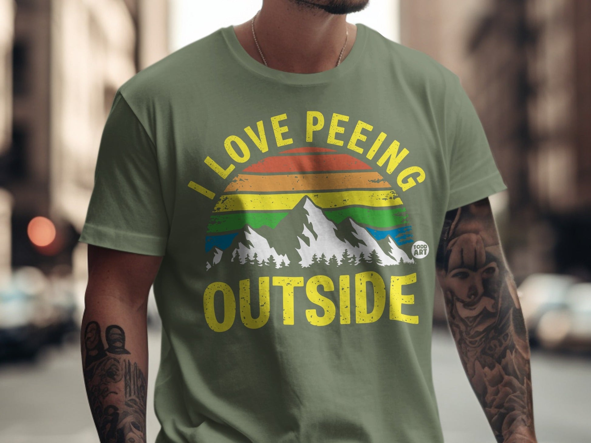 Olive t-shirt with "I love peeing outside" in rainbow and mountain graphic.