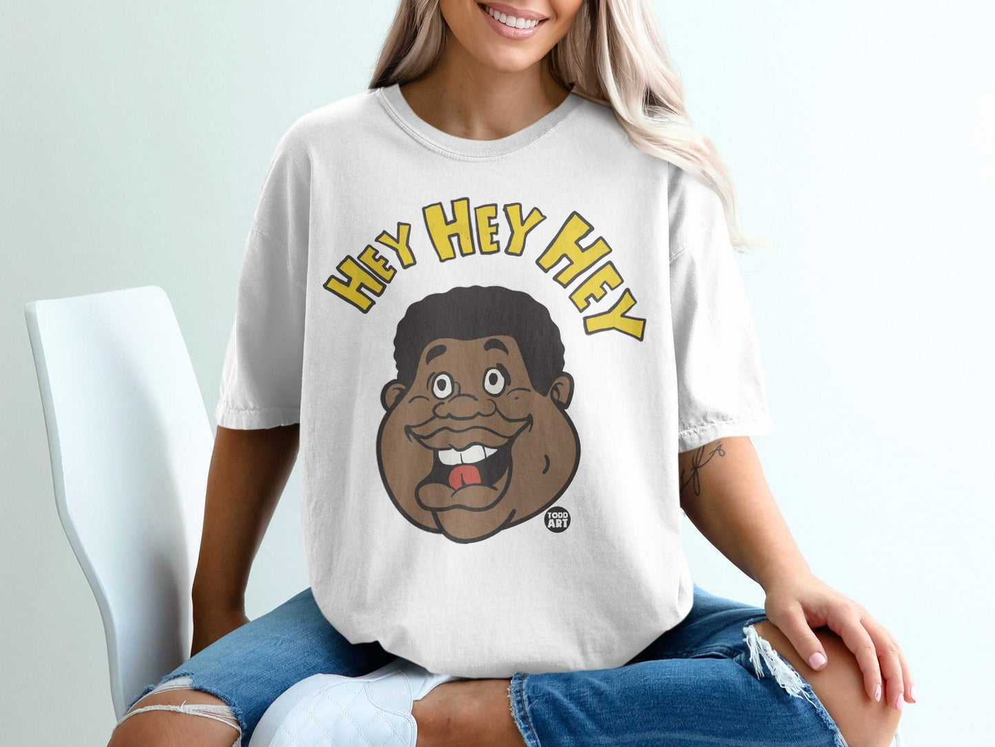 White t-shirt with "Hey Hey Hey" text and cartoon character's face.