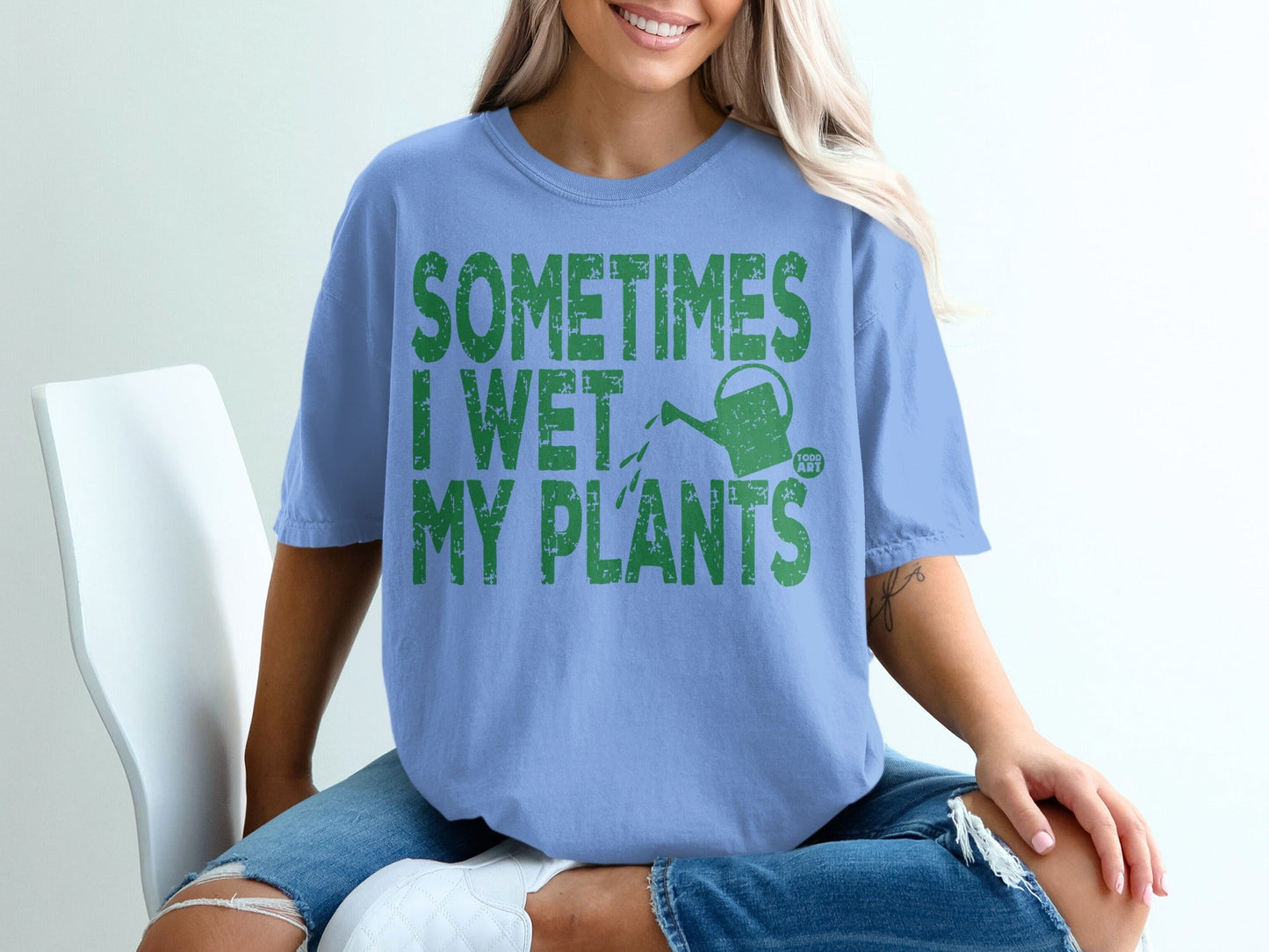 Light blue t-shirt with green text "SOMETIMES I WET MY PLANTS" and a watering can.