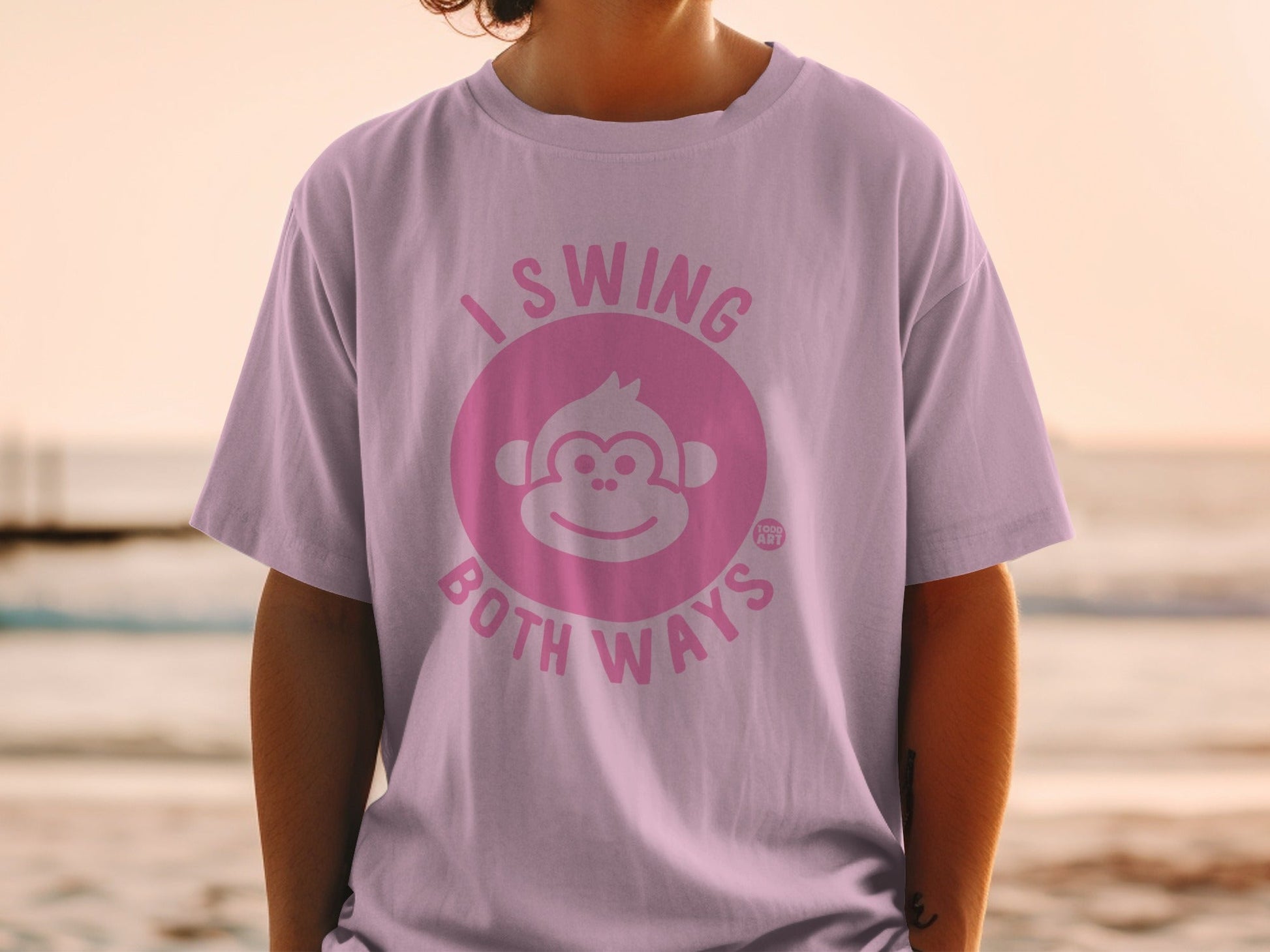 Light pink t-shirt with a monkey face logo and text "I swing both ways".