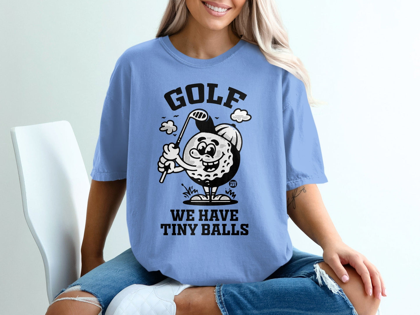 Blue t-shirt with "GOLF WE HAVE TINY BALLS" text and cartoon golf ball.