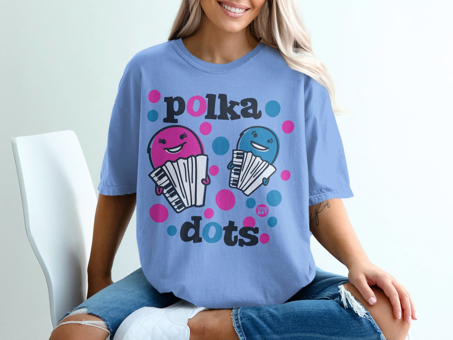 Blue t-shirt with pink and blue polka dot text and cartoon accordions.