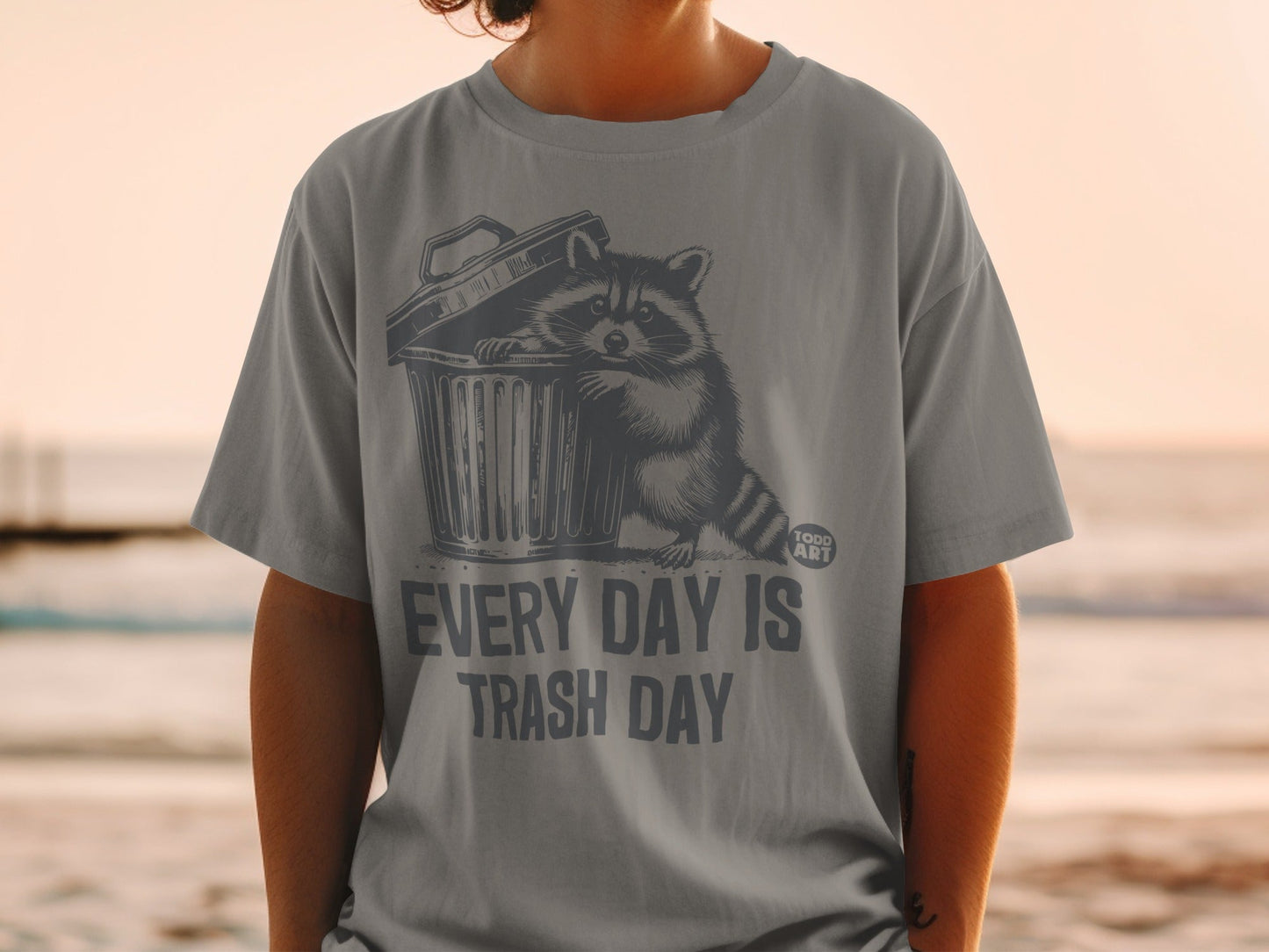Gray t-shirt with raccoon peeking out of trash can, text "EVERY DAY IS TRASH DAY".