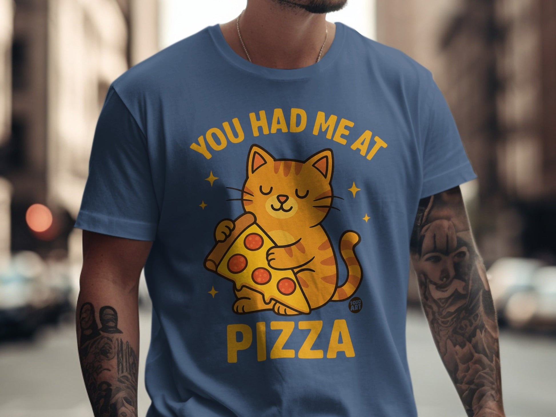 Cartoon cat holding a slice of pizza on a blue t-shirt with text.