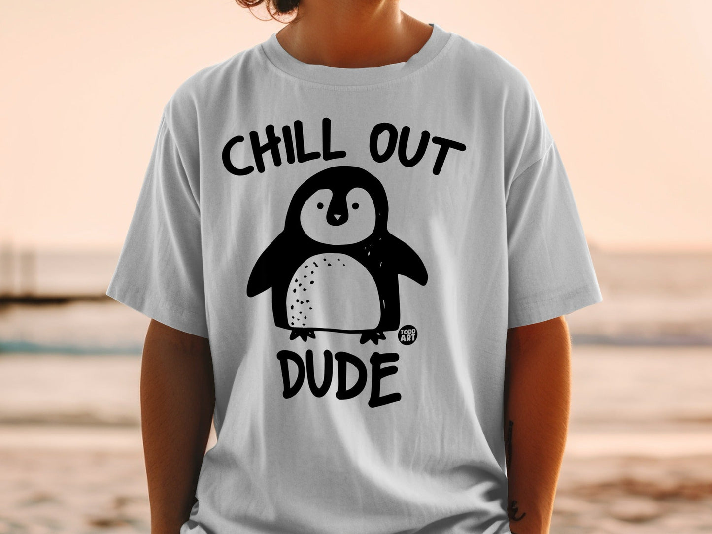 White t-shirt with black cartoon penguin and "Chill Out Dude" text.