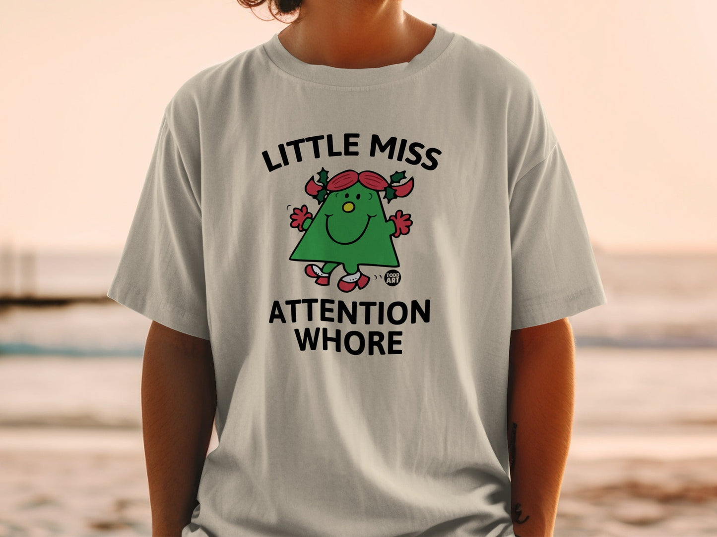 "Little Miss Attention Whore" graphic tee with a cartoon Christmas tree character.