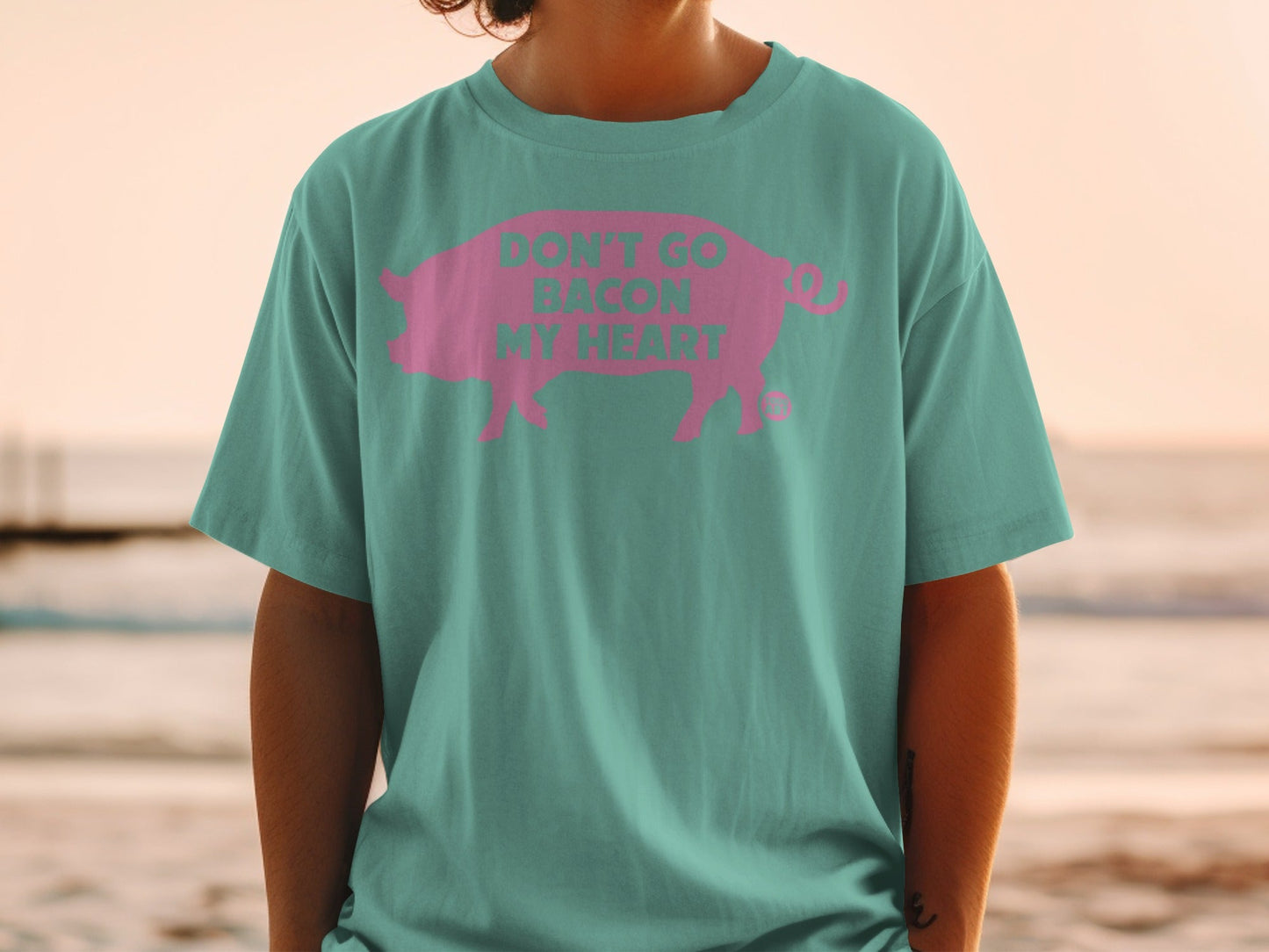 Teal t-shirt with pink pig and text "DON'T GO BACON MY HEART".
