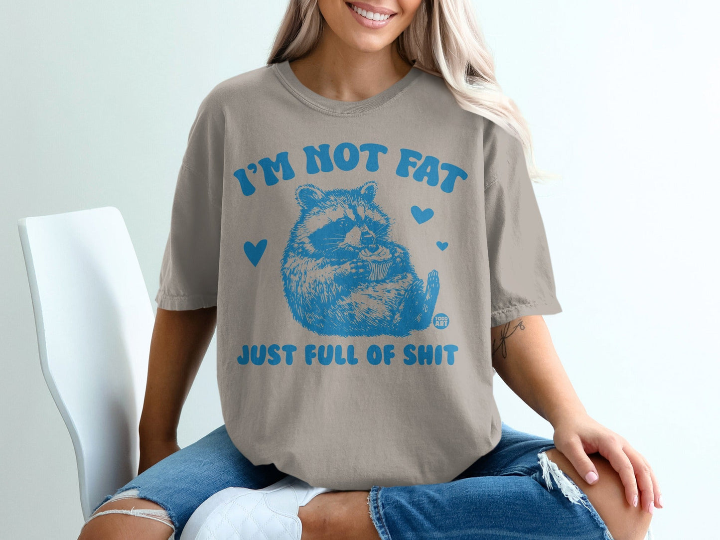 Tan t-shirt with blue raccoon graphic and text "I'm not fat just full of shit".