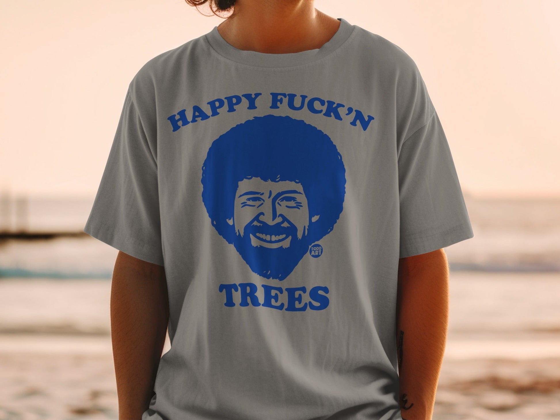 Gray t-shirt with blue graphic of Bob Ross's face and text "Happy Fuck'n Trees".