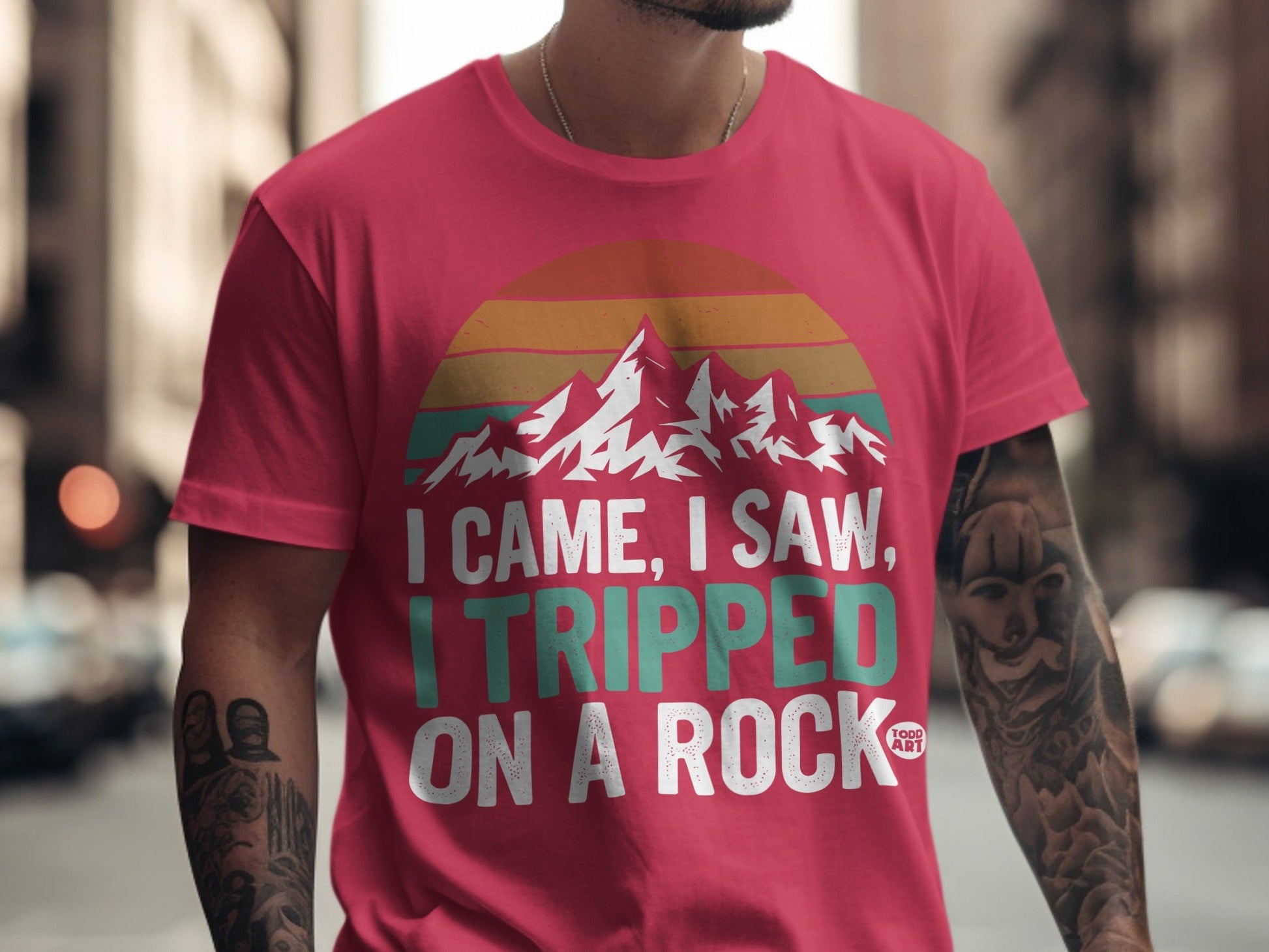 Pink t-shirt with mountains and text "I Came, I Saw, I Tripped On A Rock."